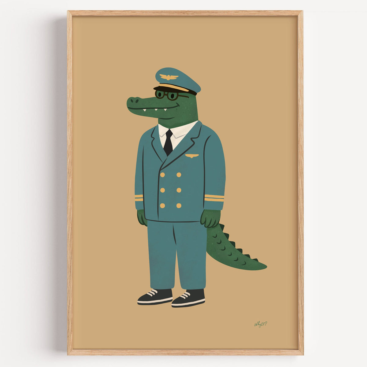 Crocodile in teal pilot uniform nursery print in a light oak frame on a plain white wall