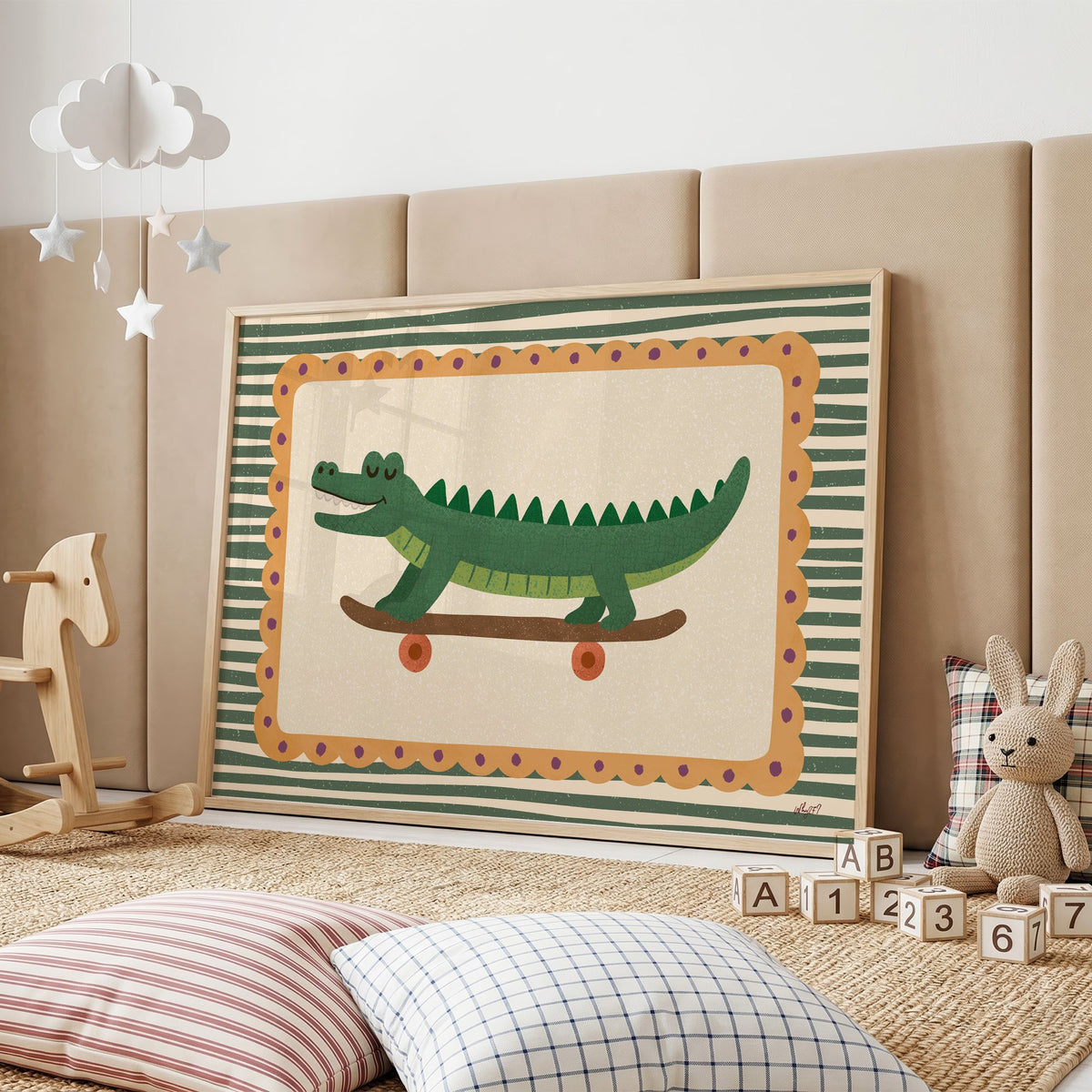 Smiling crocodile on skateboard nursery print in an oak frame on a padded wall by a wooden rocking horse
