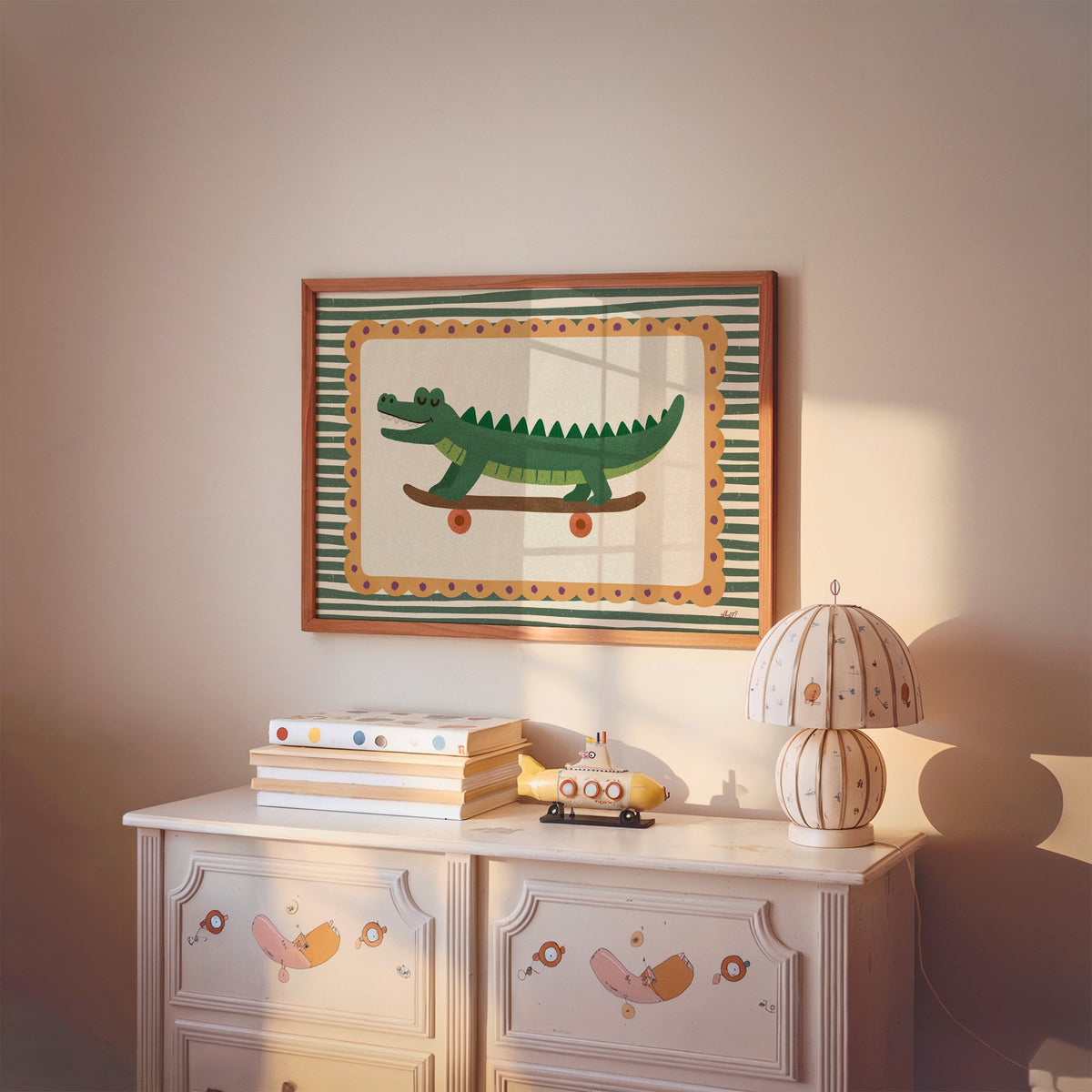 Smiling crocodile on skateboard nursery print in a cherry wood frame above a painted dresser and lamp