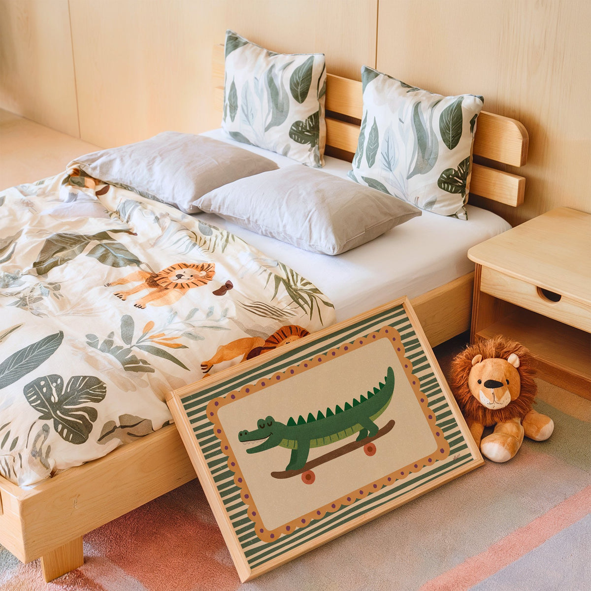 Smiling crocodile on skateboard nursery print in an oak frame leaning on a kids bed by a lion plush