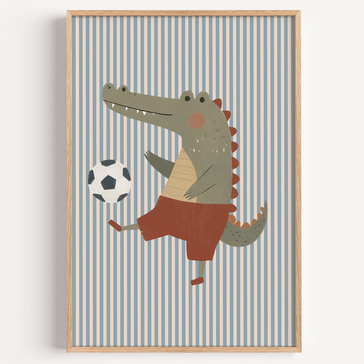 Crocodile soccer ball nursery print in a light oak frame on a plain white wall