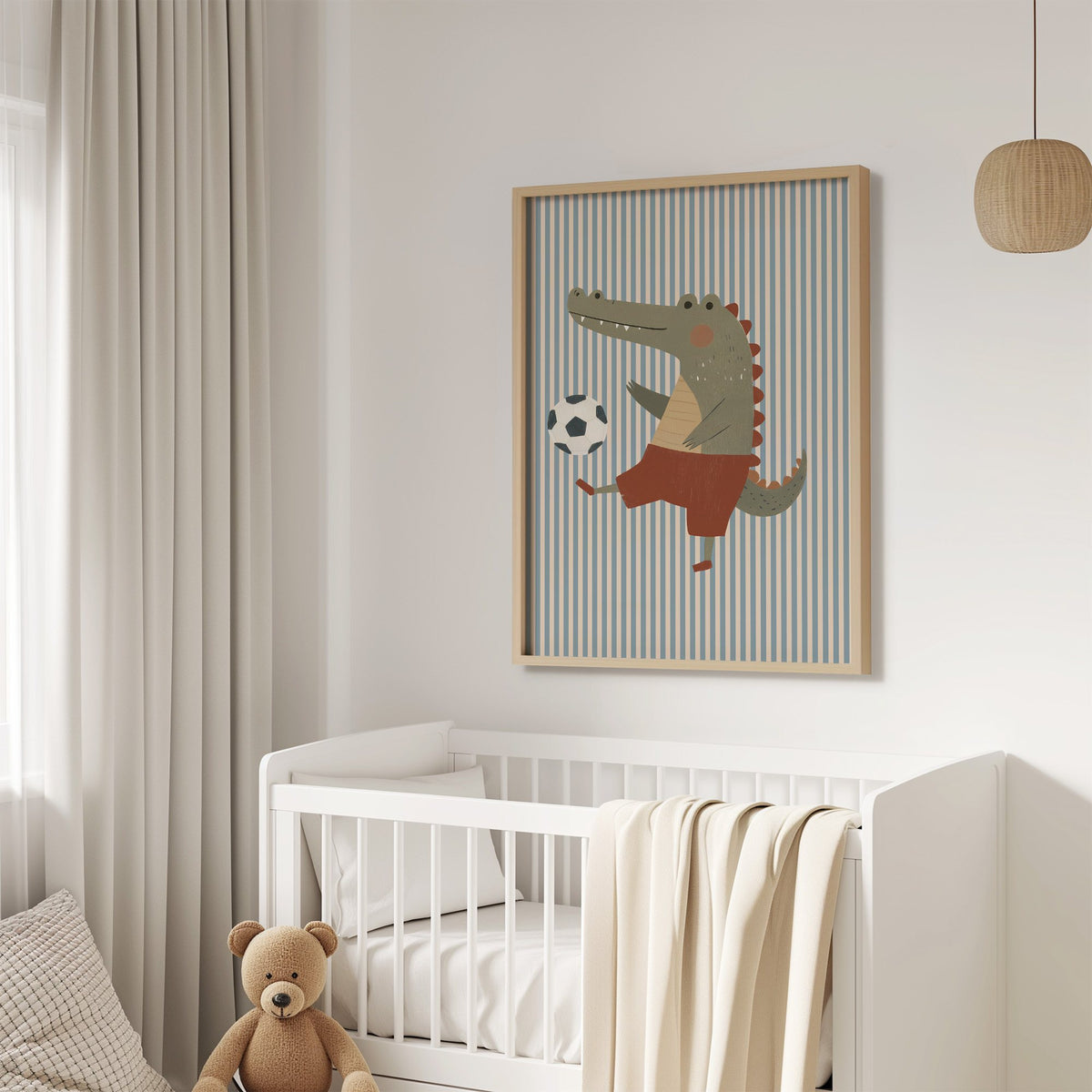 Crocodile soccer ball nursery print in an oak frame above a white crib with a teddy bear