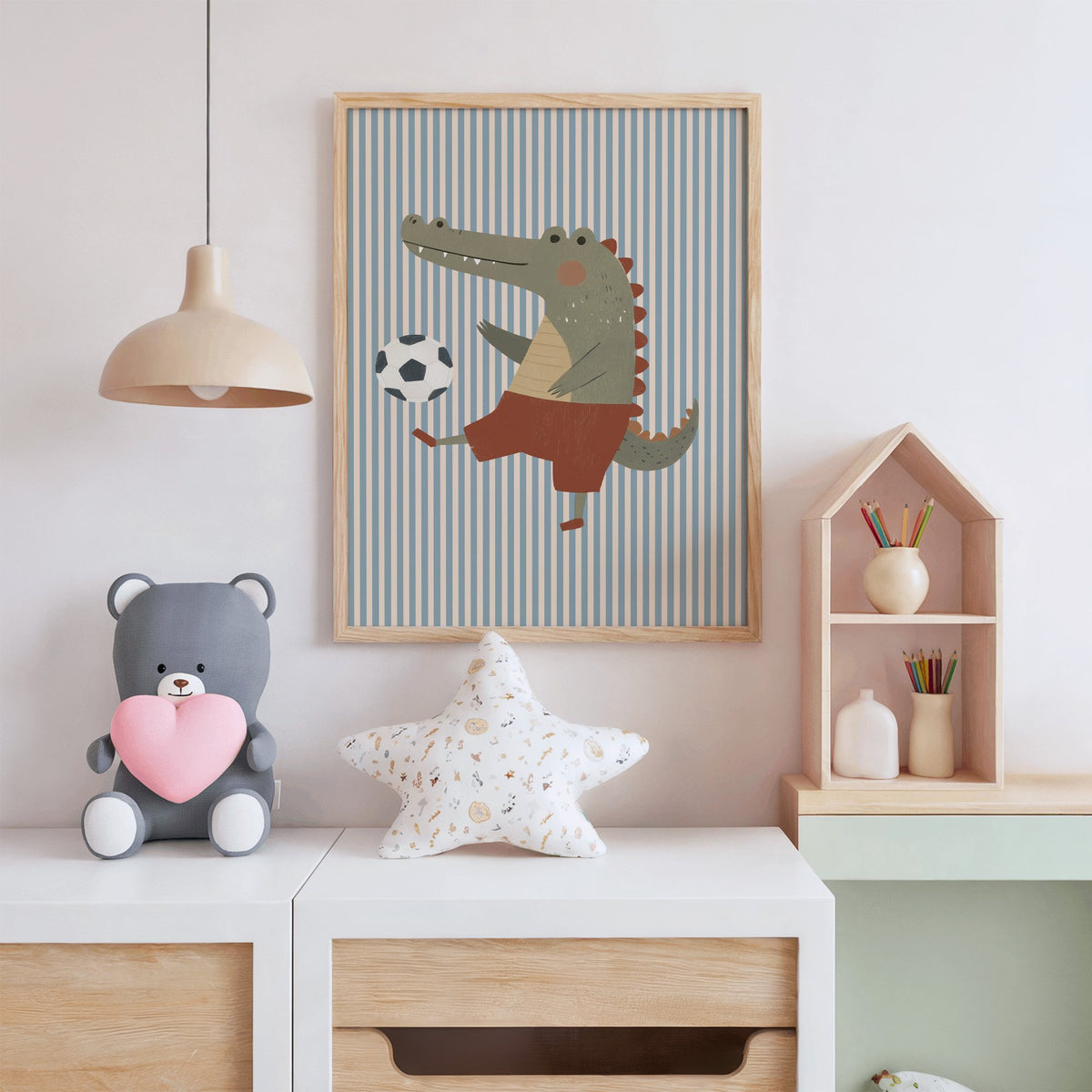 Crocodile soccer ball nursery print in an oak frame above a white dresser with a star pillow and house shelf