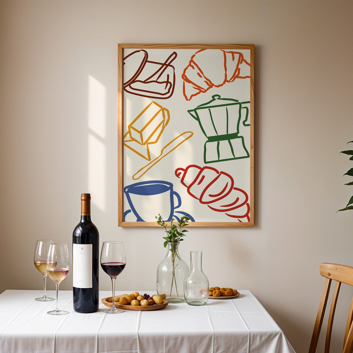 Croissant and coffee doodle print in an oak frame above a table laid with red wine and glasses