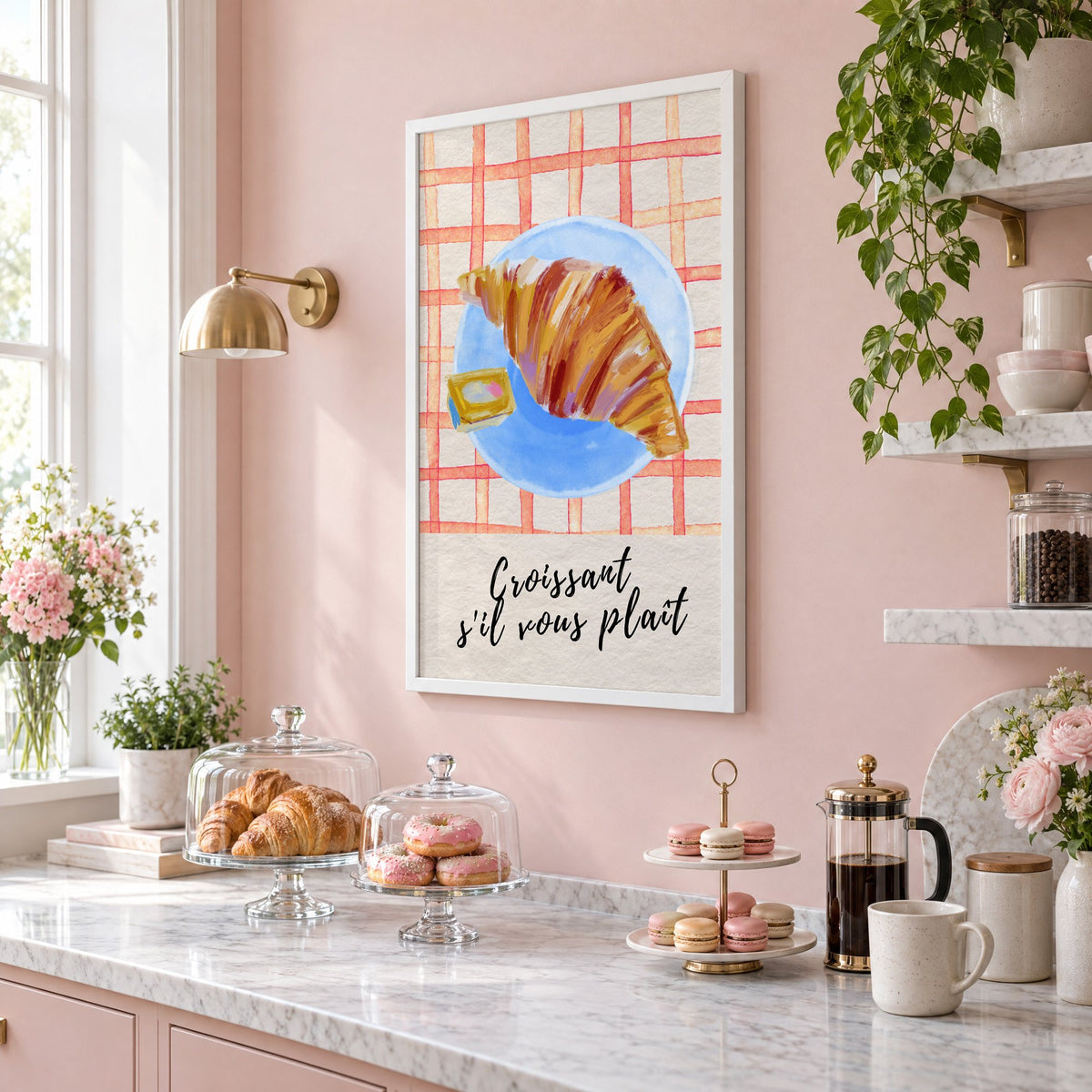 Croissant s'il vous plait blue plate print in a white frame on a blush pink wall above a patisserie counter with croissants and macarons, seen at an angle