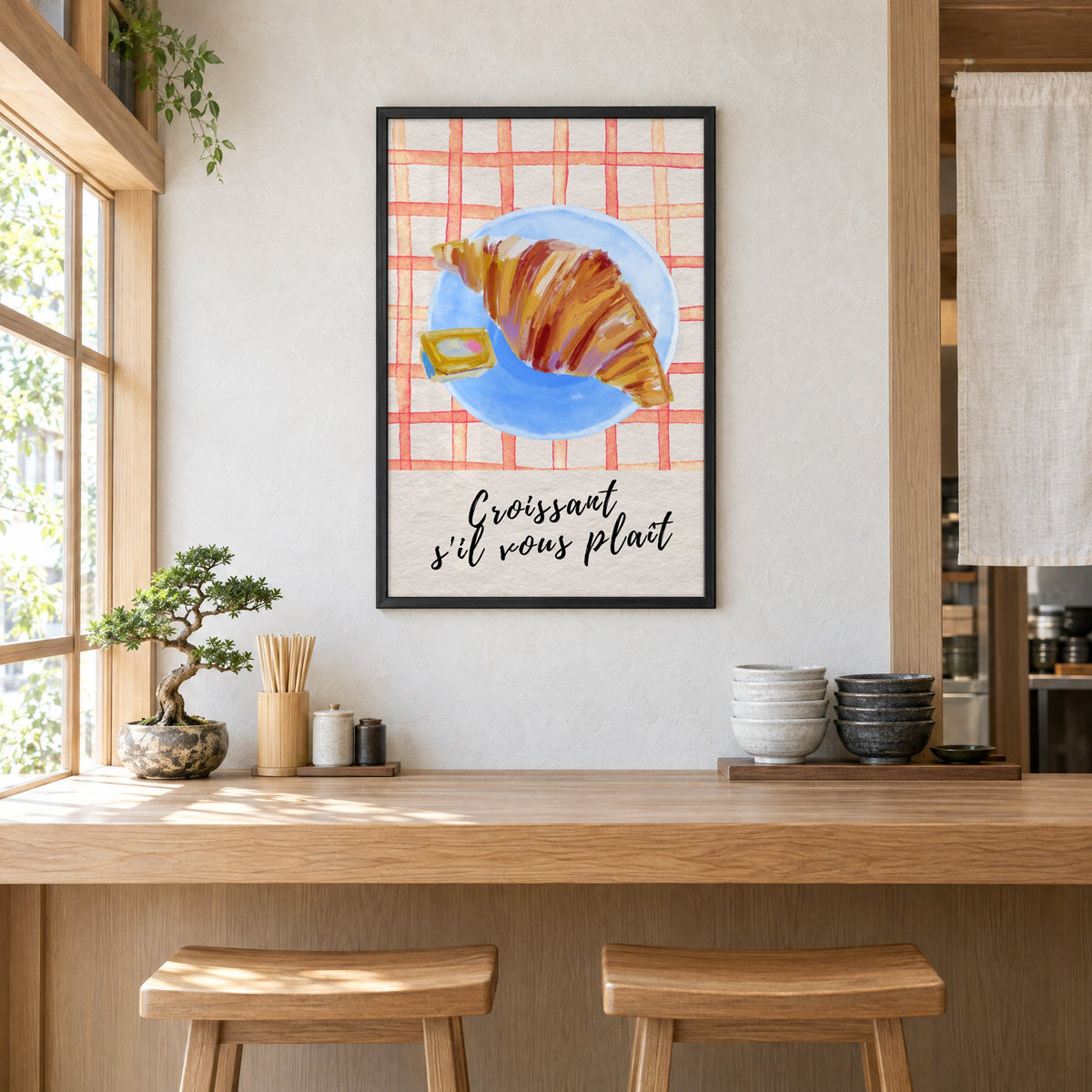 Croissant s'il vous plait blue plate print in a black frame above a light wood ramen counter with stools and stacked bowls