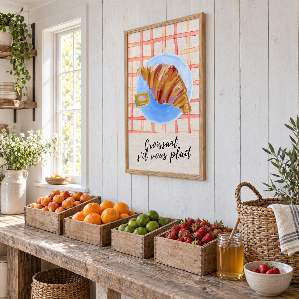 Croissant s'il vous plait blue plate print in an oak frame on white plank walls above wooden crates of fresh fruit, seen at an angle