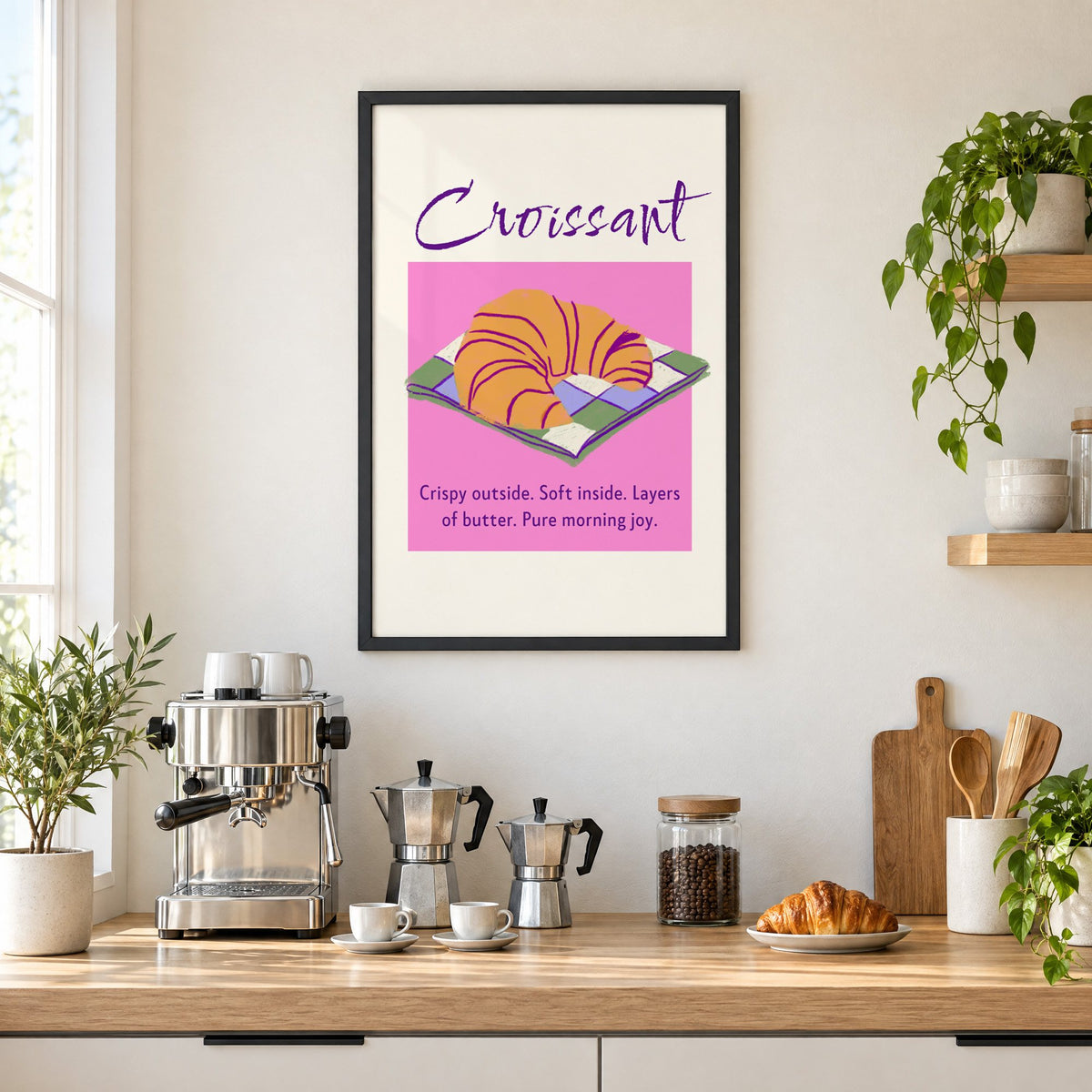Croissant on checkered napkin pink panel print in a black frame above a home espresso bar with moka pots and espresso cups