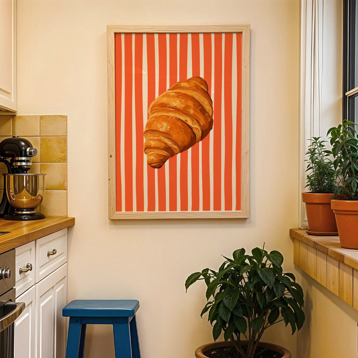 Painted croissant print in a wood frame on a yellow tiled kitchen wall