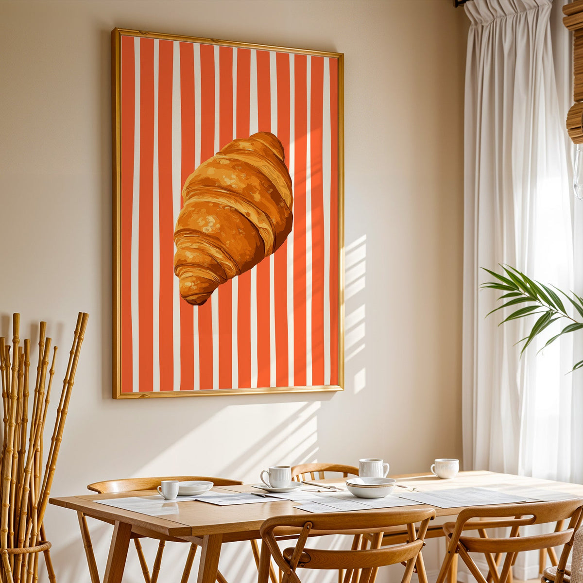 Painted croissant print in a gold frame above a sunlit breakfast table