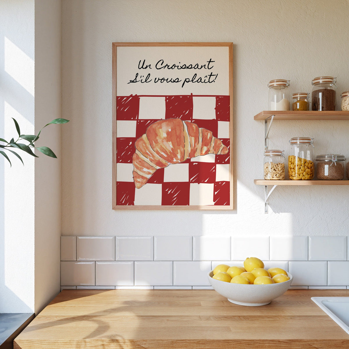 Un Croissant red check print in an oak frame on a subway-tiled kitchen wall beside open shelves of pantry jars