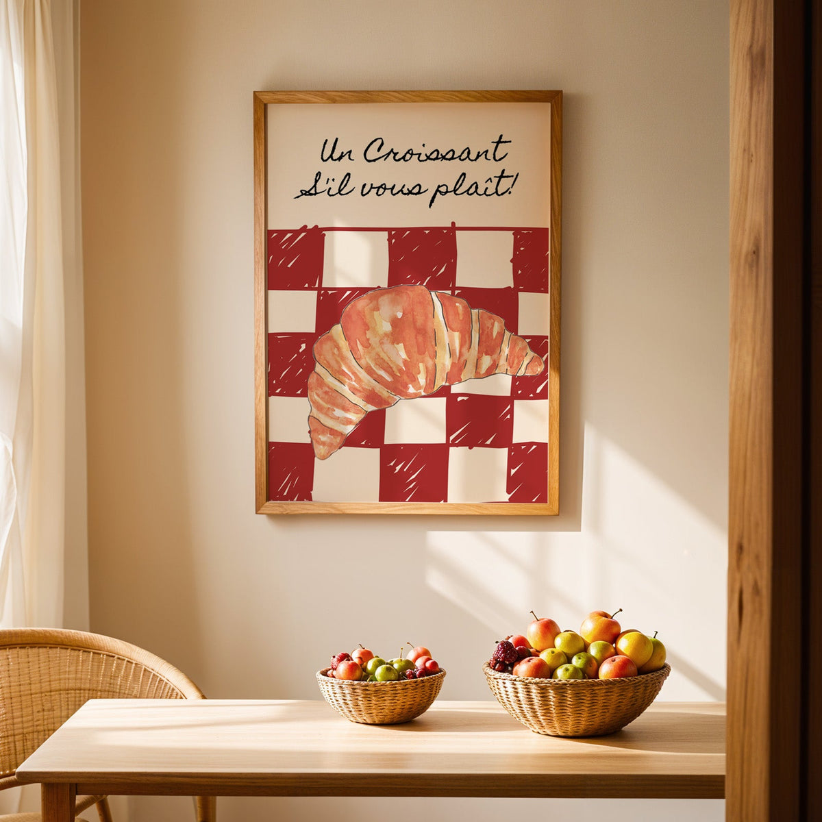 Un Croissant red check print in an oak frame above a light wood dining table with baskets of fruit
