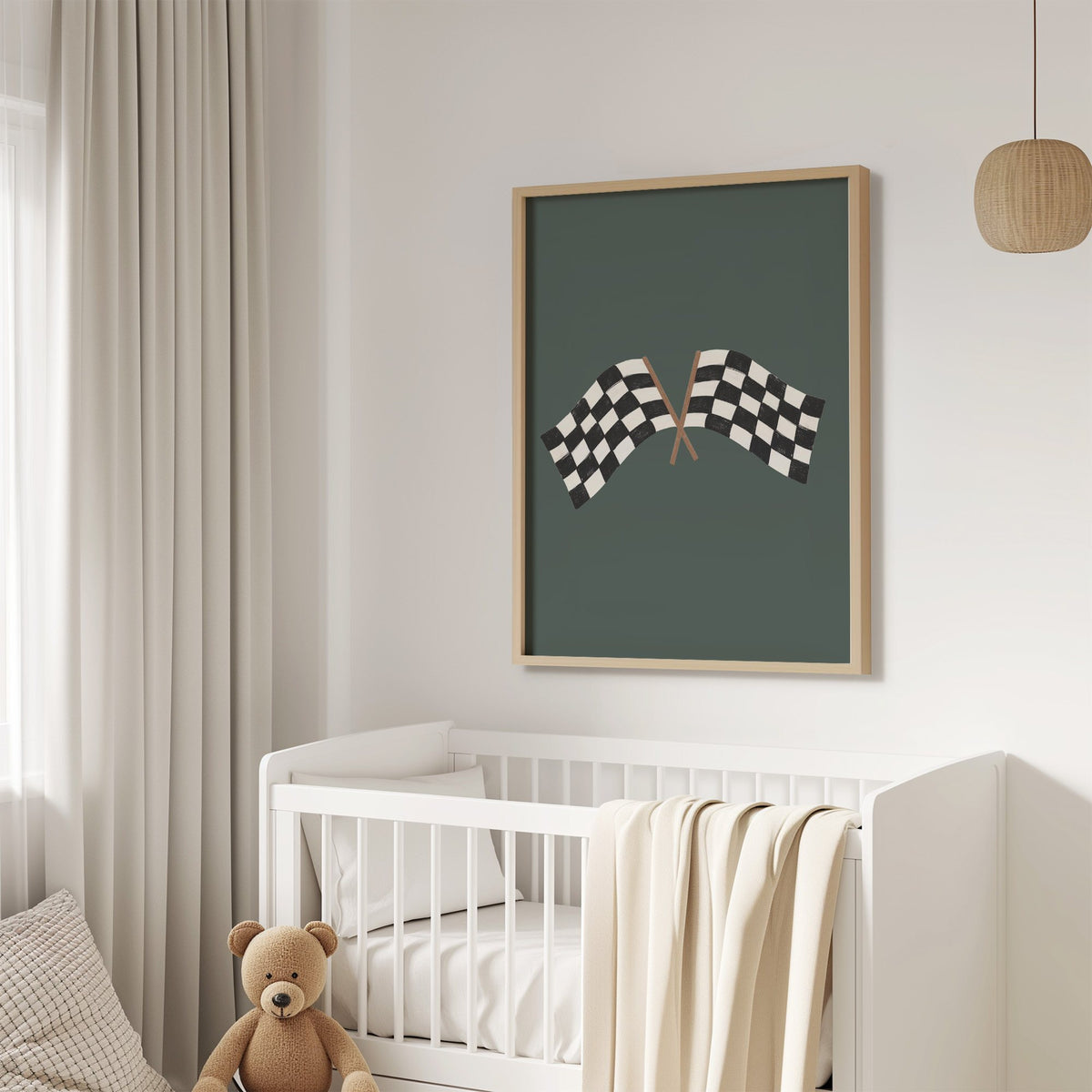 Crossed checkered racing flags nursery print in an oak frame above a white crib with a teddy bear