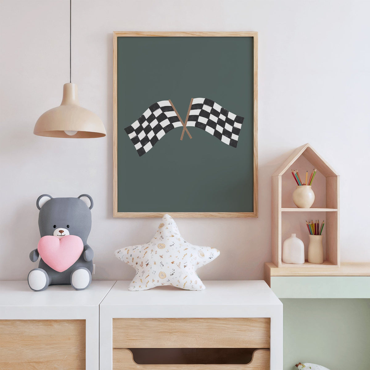Crossed checkered racing flags nursery print in an oak frame above a white dresser with a star pillow and house shelf