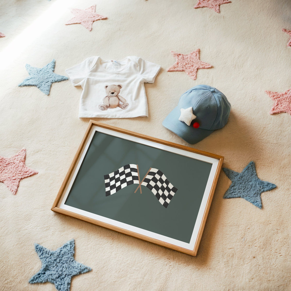 Landscape crossed checkered racing flags nursery print in a matted oak frame on a star rug with a baby tee
