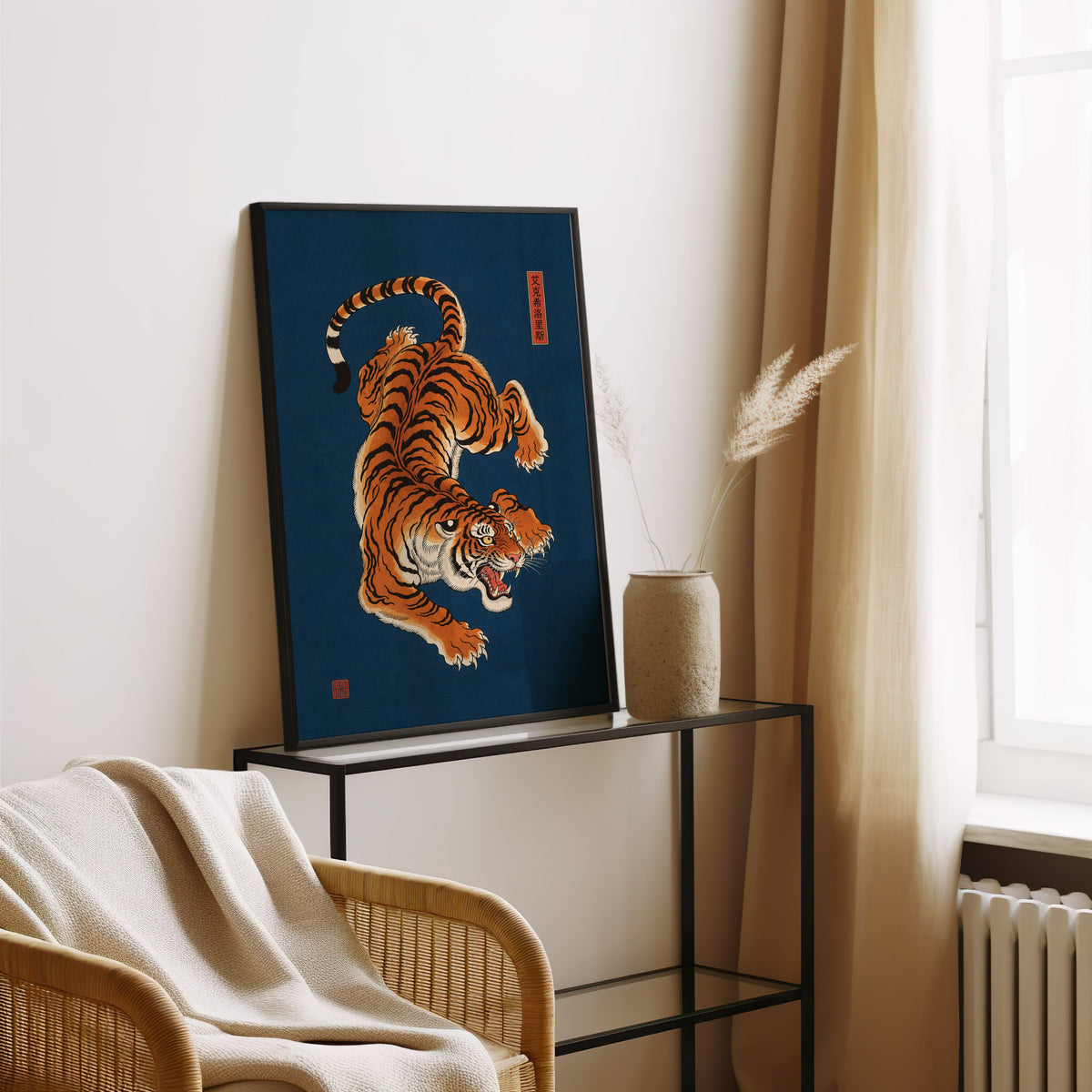 orange tiger on navy blue print in a black frame leaning on a glass console beside pampas grass