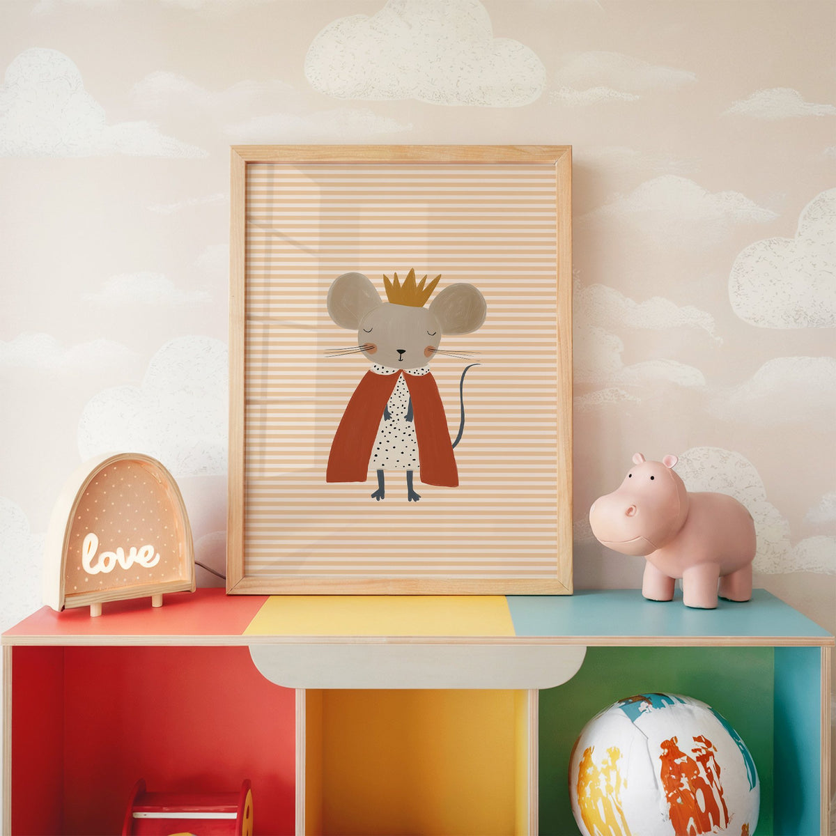 Crowned mouse red cape nursery print in an oak frame on a rainbow toy shelf against cloud wallpaper