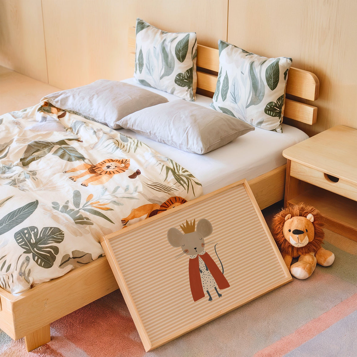 Landscape crowned mouse red cape nursery print in an oak frame leaning on a kids bed by a lion plush