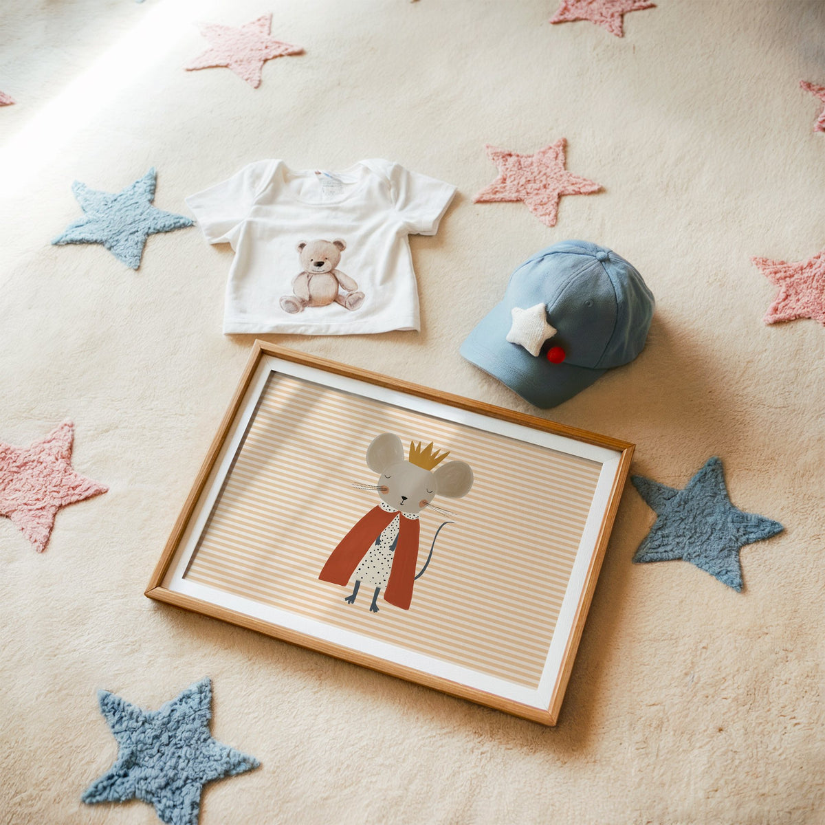 Landscape crowned mouse red cape nursery print in a matted oak frame on a star rug with a baby tee