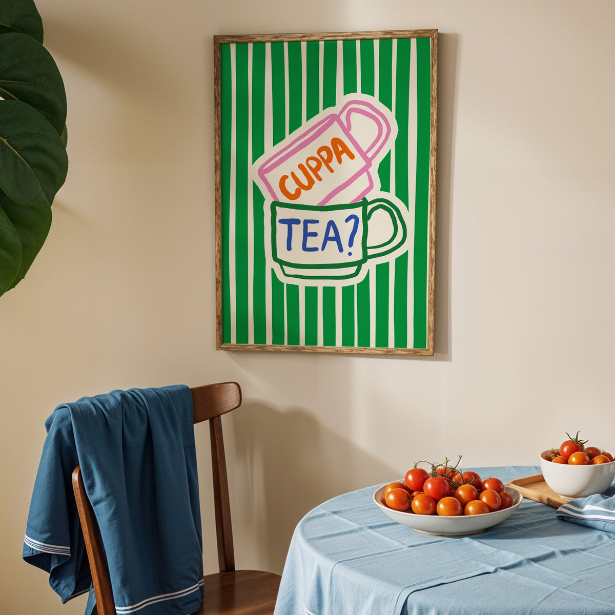 Cuppa tea print in an oak frame above a blue linen table with ripe tomatoes