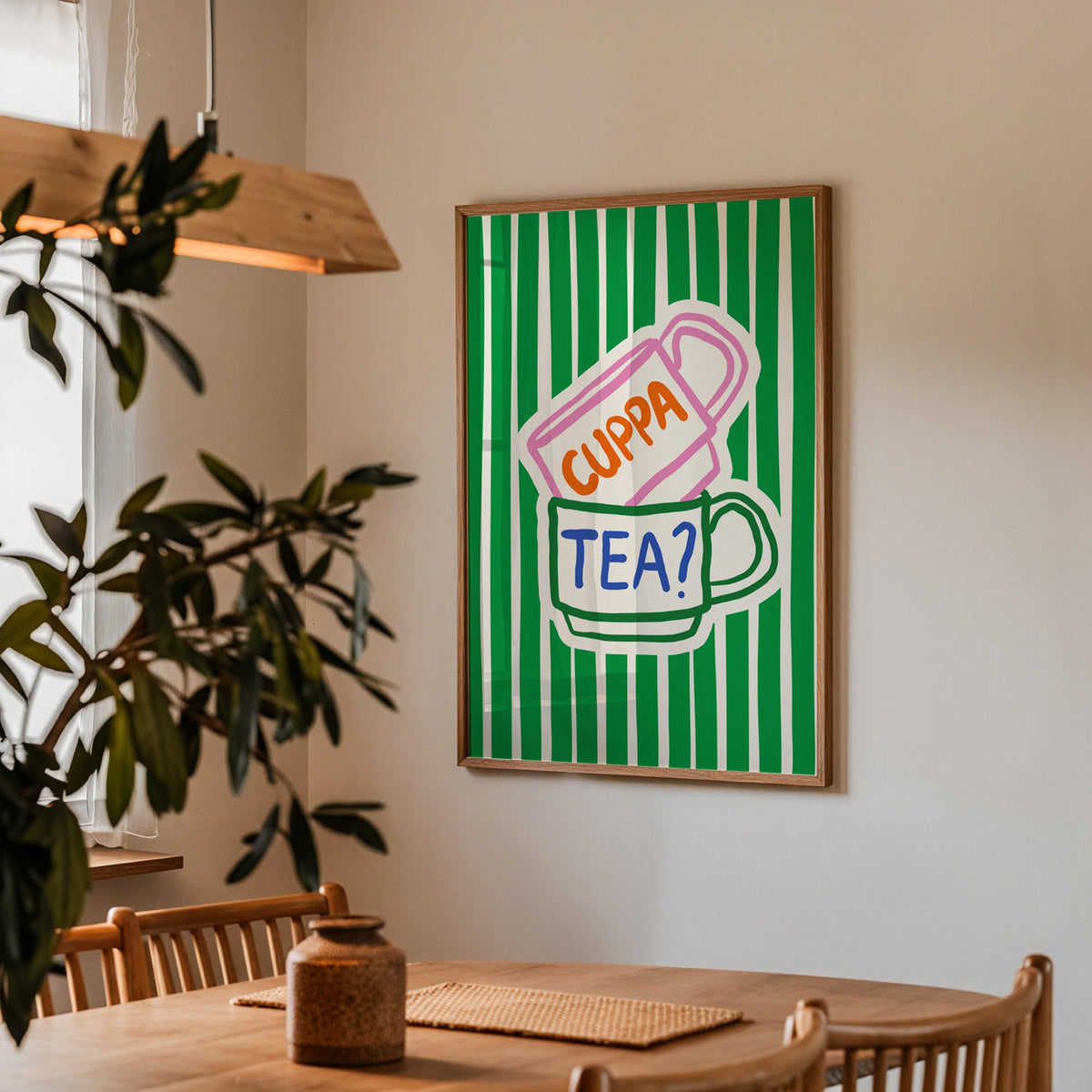 Cuppa tea print in a walnut frame above a dining table beside an olive tree