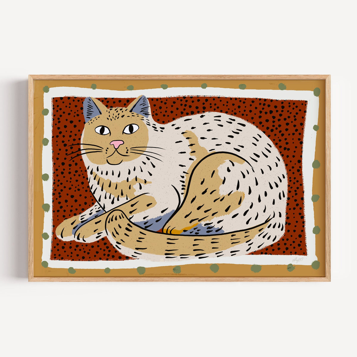 Curled cream cat on rust dots nursery print in a light oak frame on a plain white wall