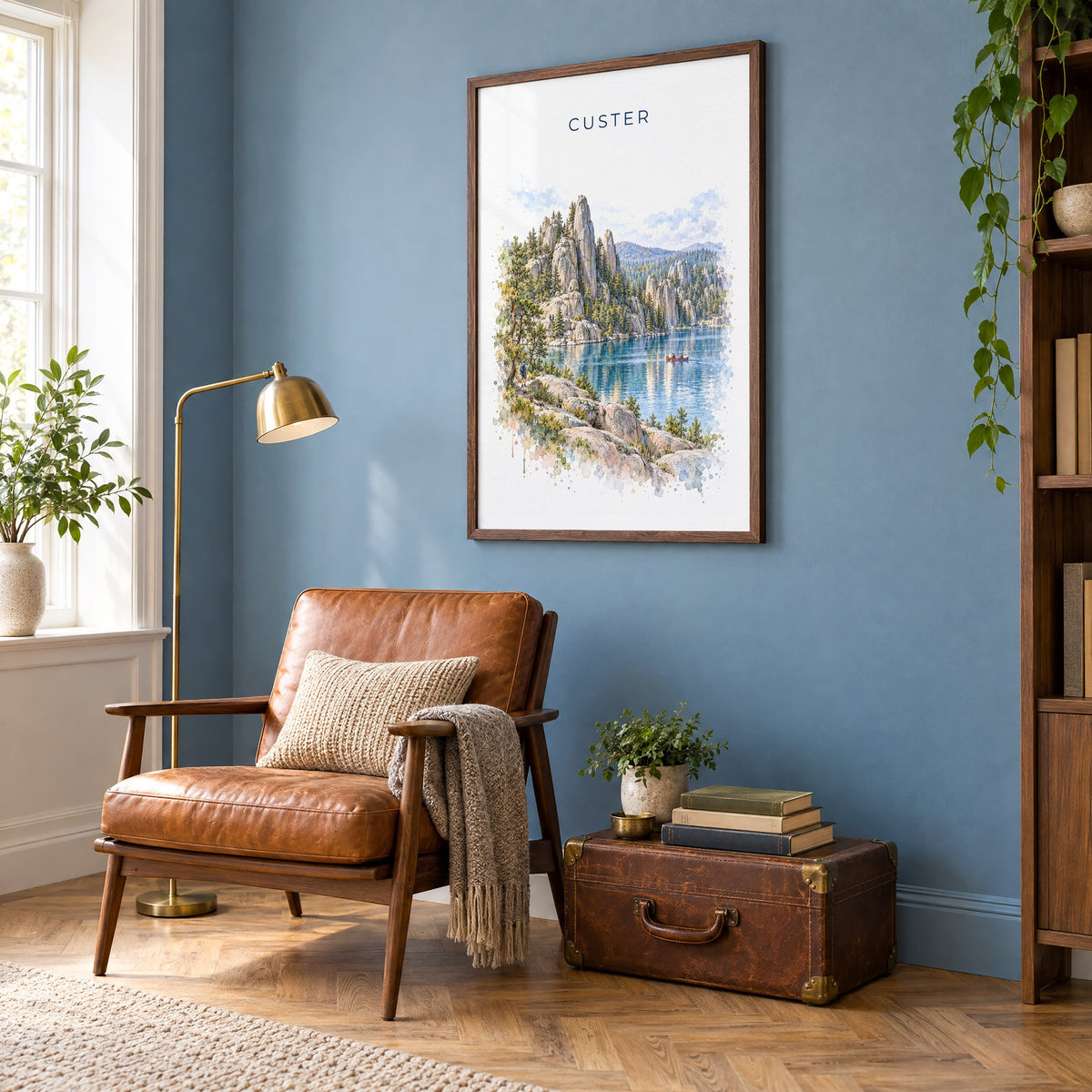 Custer State Park watercolor print in a walnut frame on a blue wall above a leather armchair in a reading nook