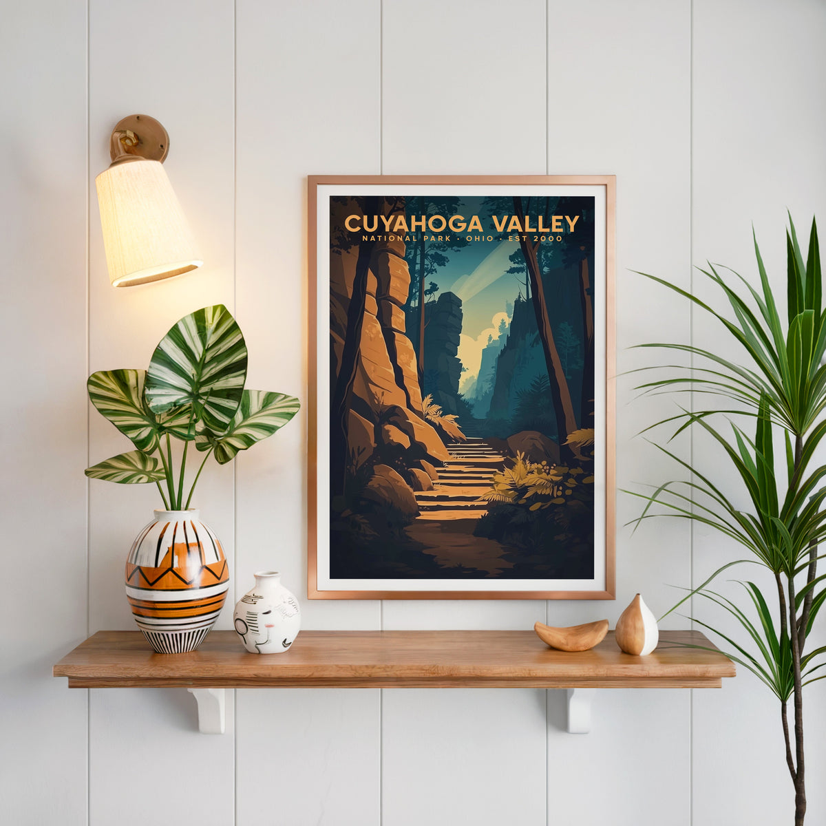 Cuyahoga Valley print in a copper frame above an oak shelf on white shiplap with a sconce