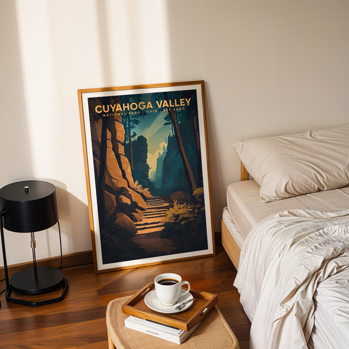 Cuyahoga Valley print in an oak frame leaning on a bedroom floor beside the bed and a tray