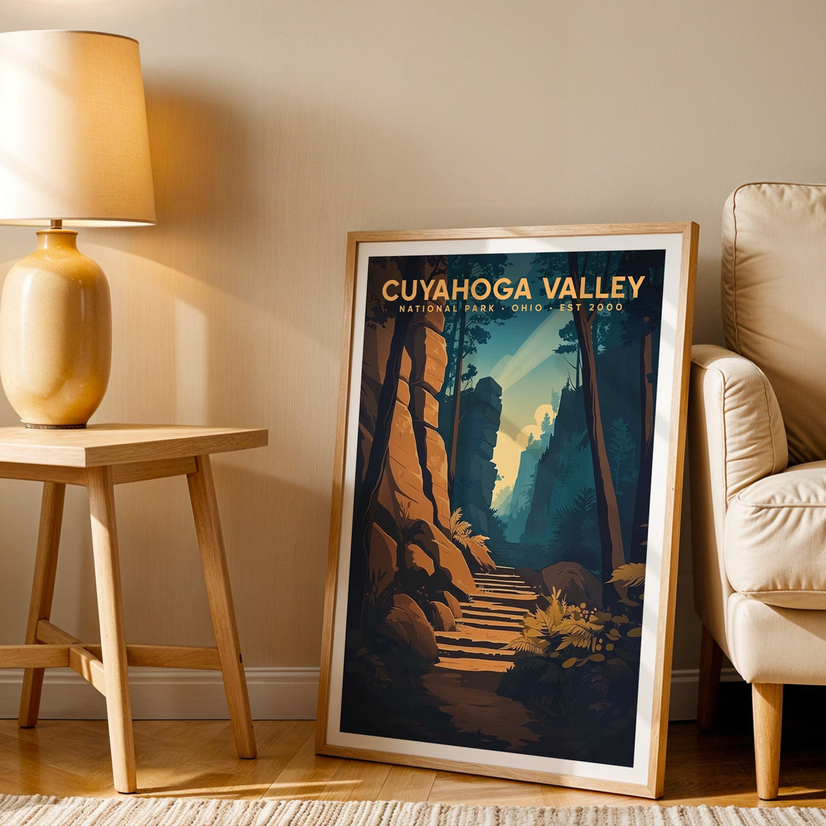 Cuyahoga Valley print in an oak frame beside a cream armchair and an amber lamp in warm light