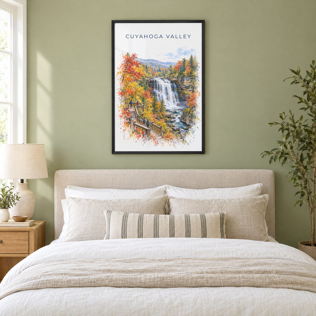 Cuyahoga Valley National Park watercolor print in a black frame above an upholstered headboard in a sage green bedroom