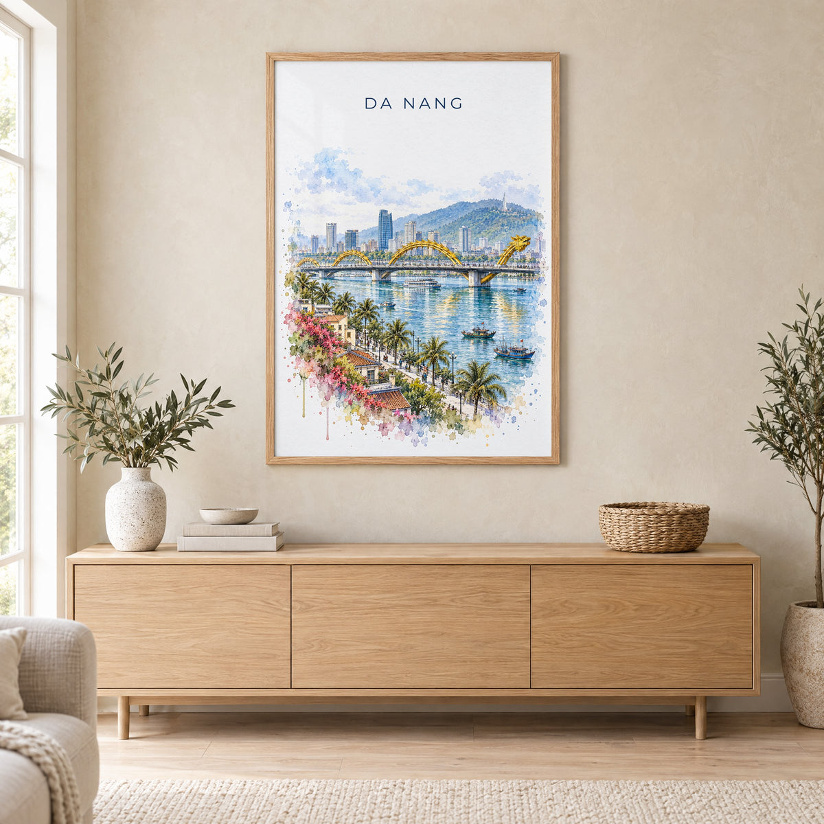 Da Nang watercolor print in an oak frame above a light wood sideboard in a Scandinavian living room