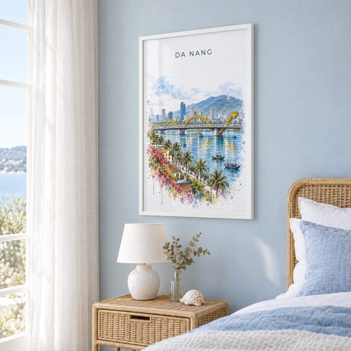 Da Nang watercolor print in a white frame on a pale blue wall beside a rattan bed in a coastal bedroom