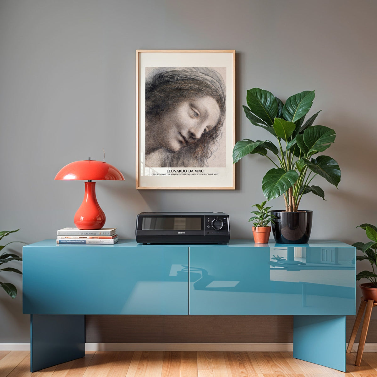 Da Vinci study print in an oak frame above a teal sideboard with a red lamp