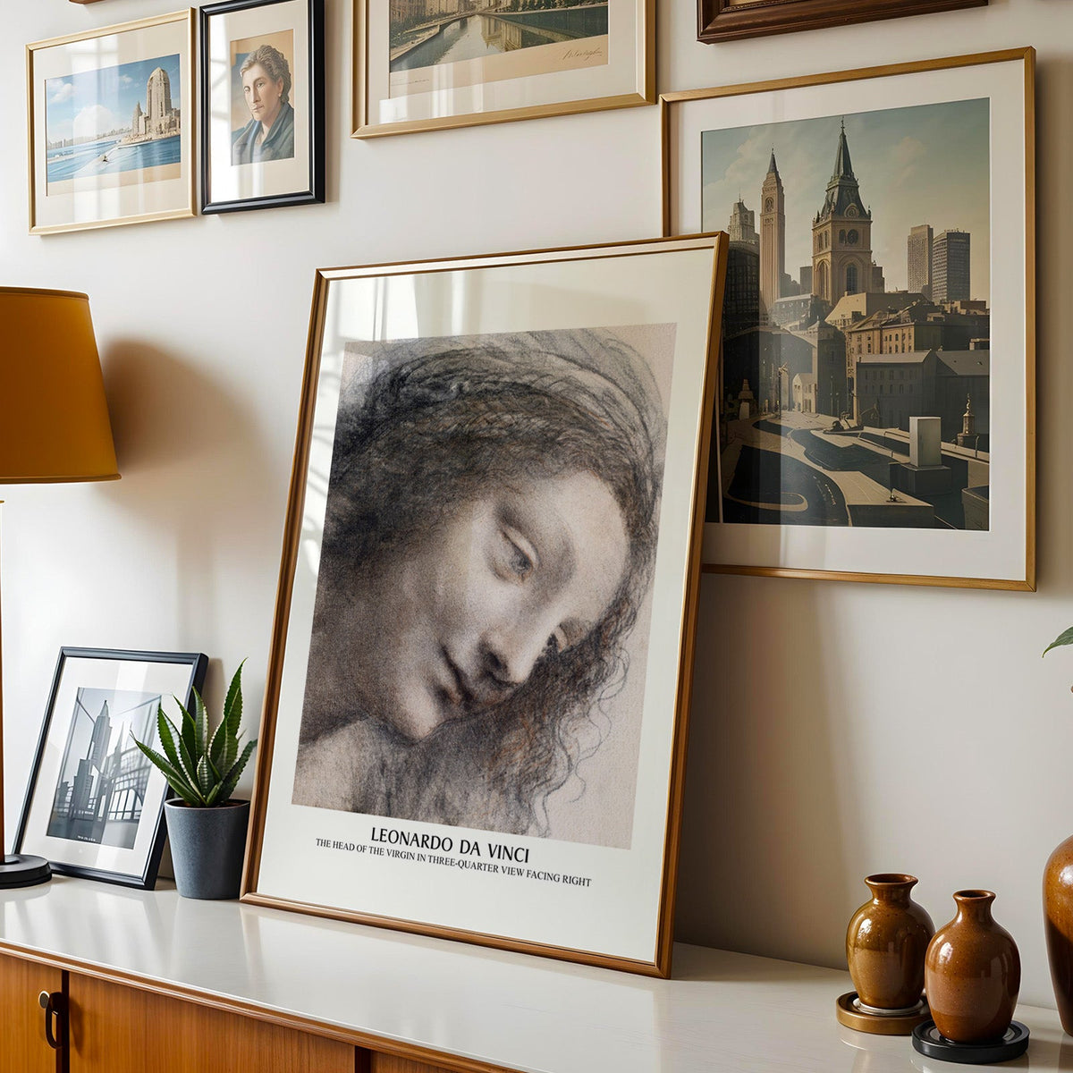 Renaissance drawing print shown in a gold frame leaning on a sideboard in a gallery wall