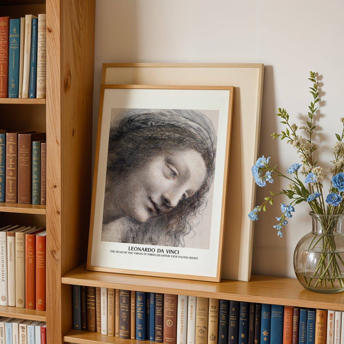 Leonardo da Vinci print in an oak frame leaning on a bookshelf beside flowers