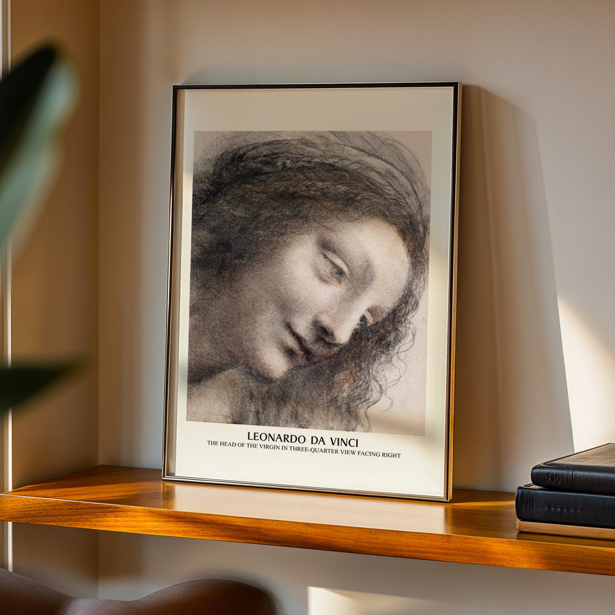 Virgin head study print in a black frame on a walnut shelf in evening light