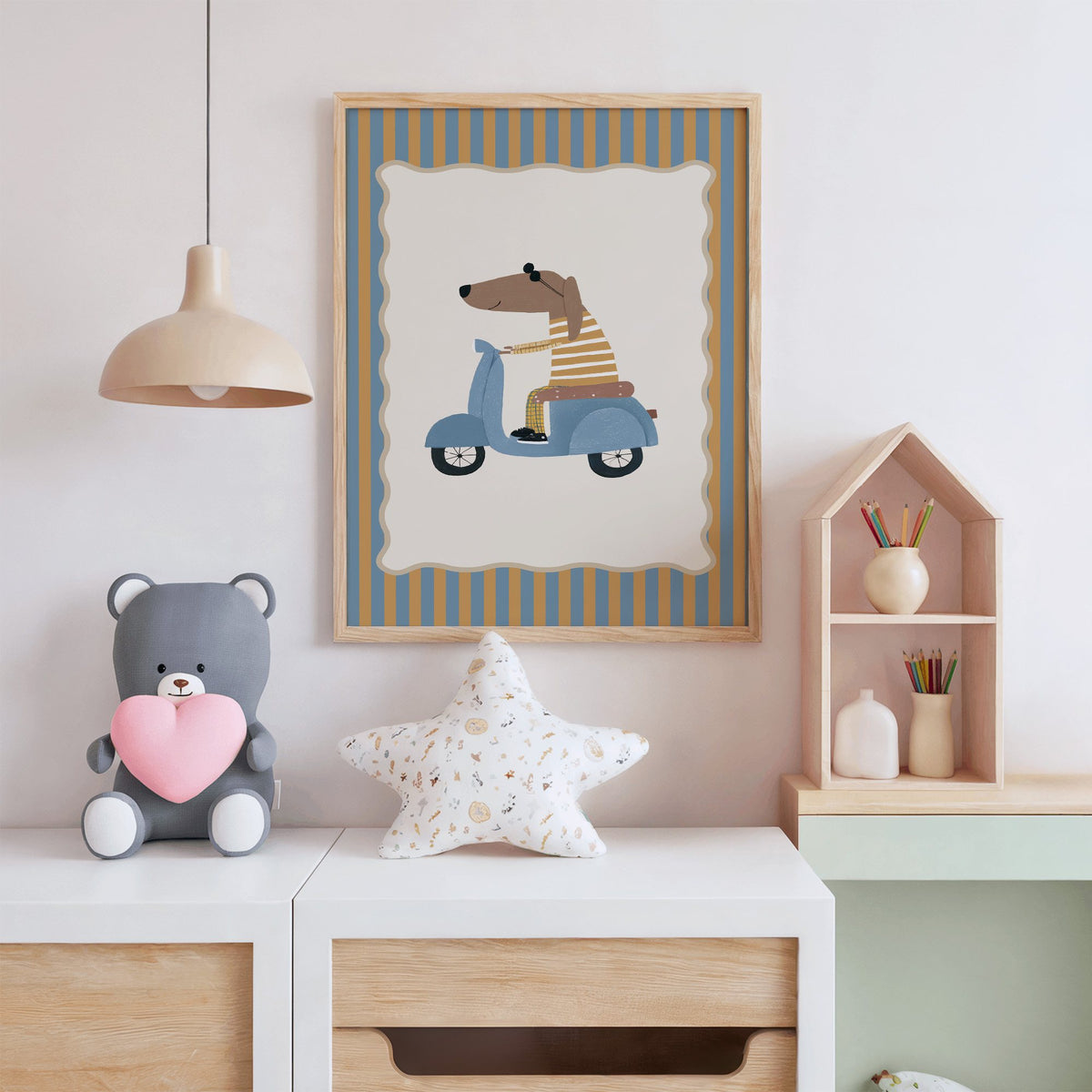 Dachshund on blue scooter nursery print in an oak frame above a white dresser with a star pillow and house shelf