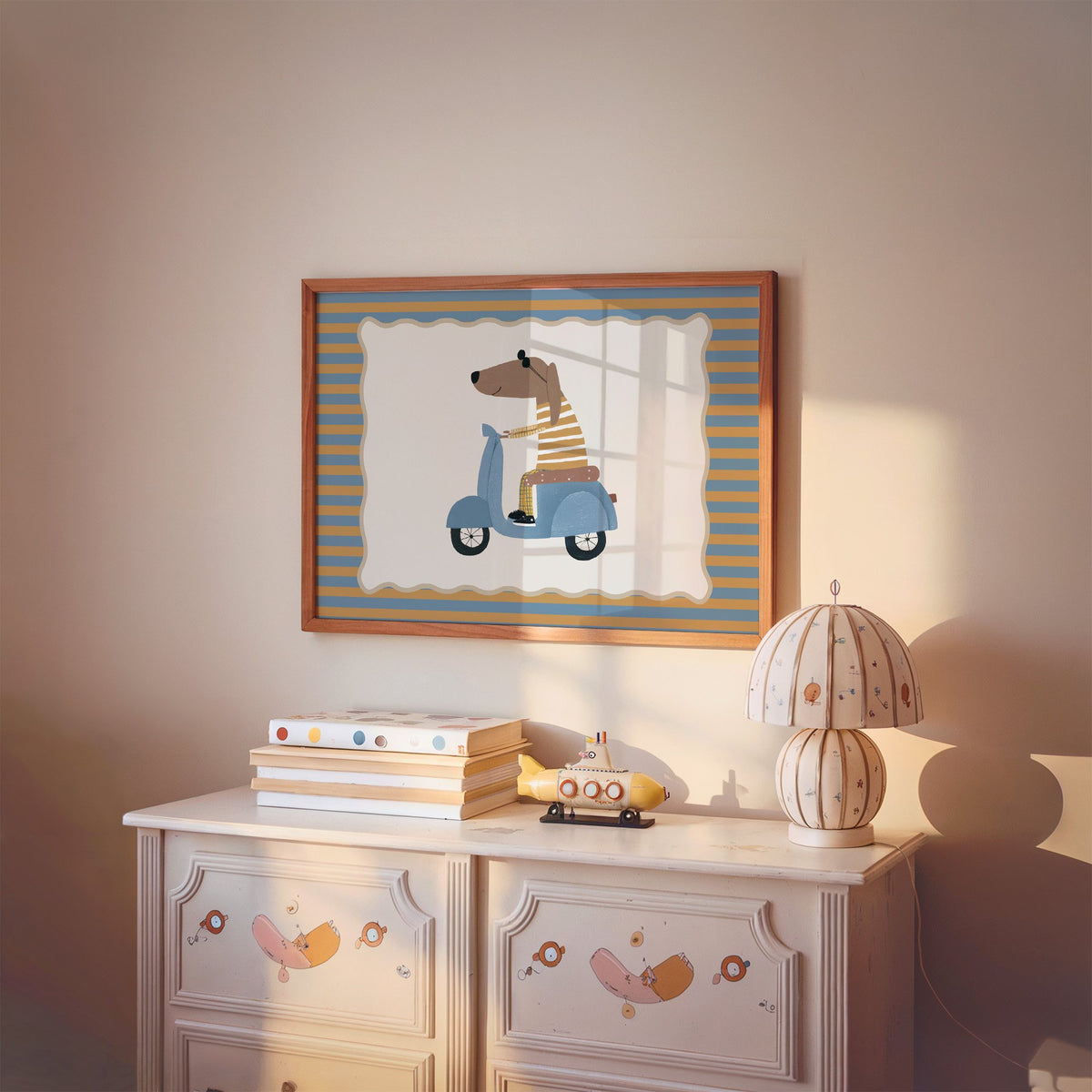Landscape dachshund on blue scooter nursery print in a cherry wood frame above a painted dresser and lamp