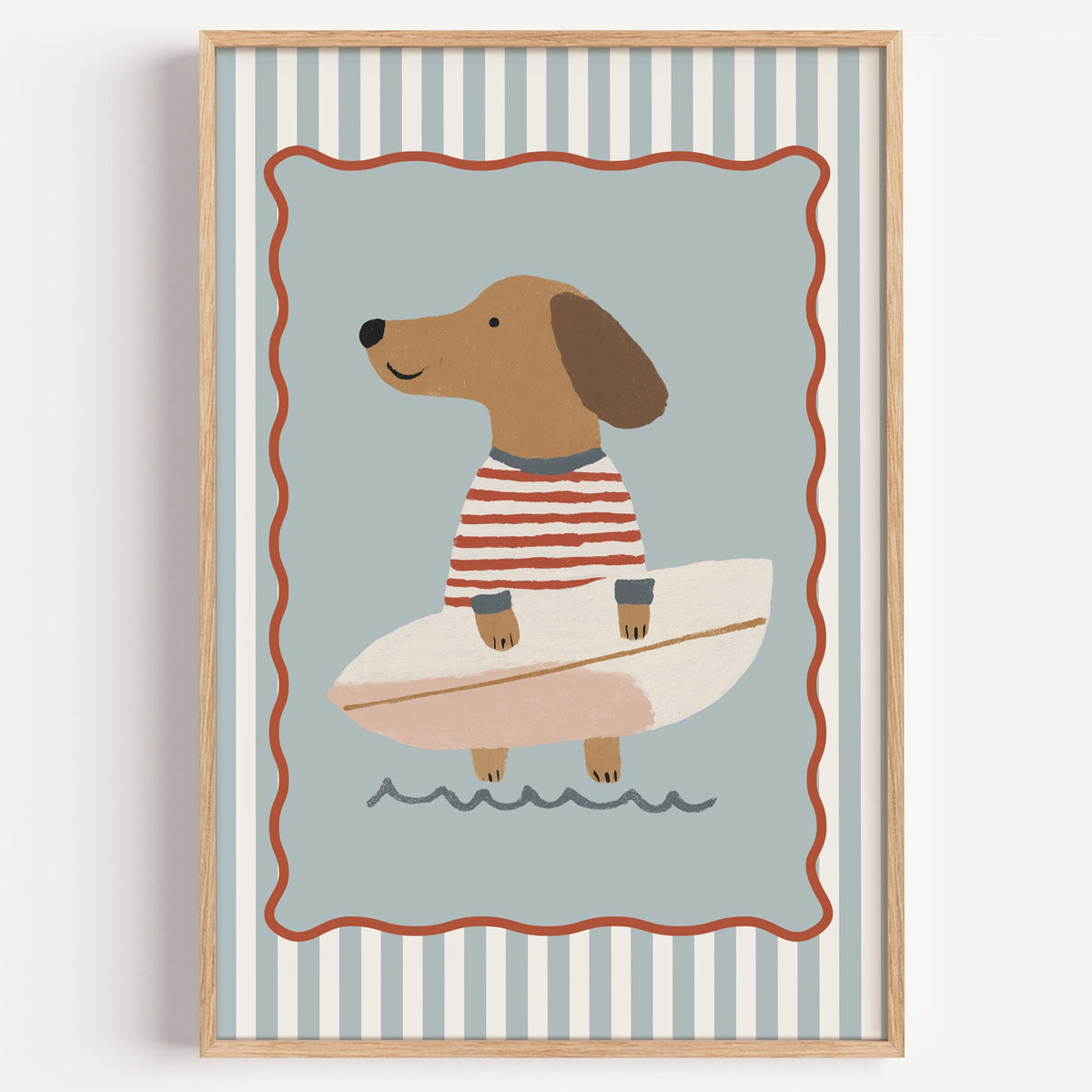 Dachshund holding surfboard nursery print in a light oak frame on a plain white wall