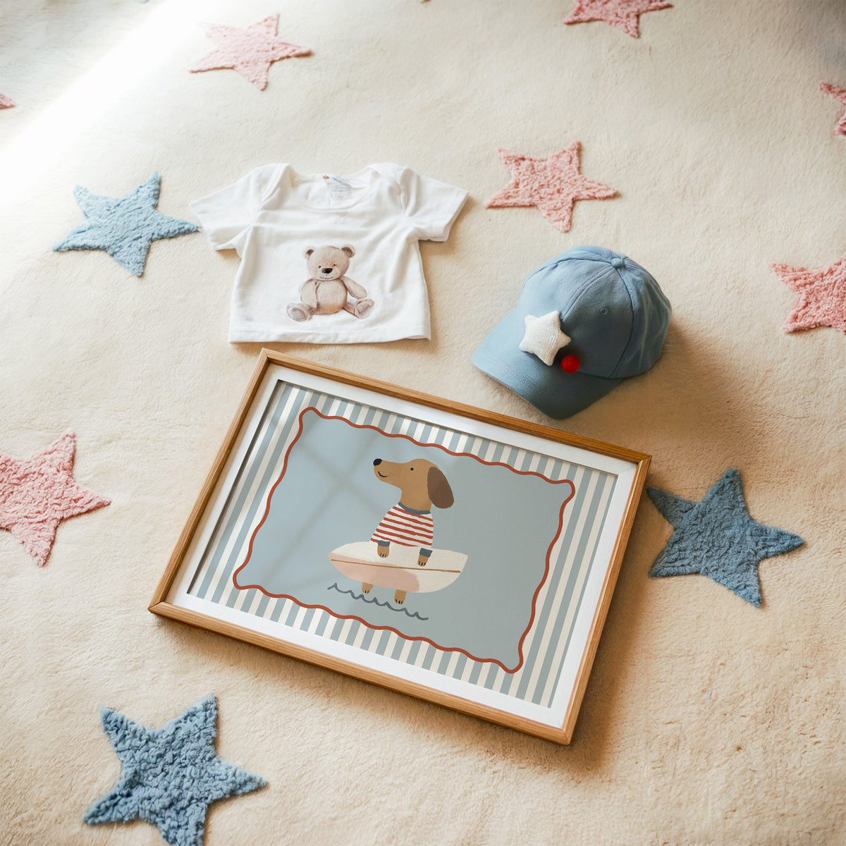 Landscape dachshund holding surfboard nursery print in a matted oak frame on a star rug with a baby tee