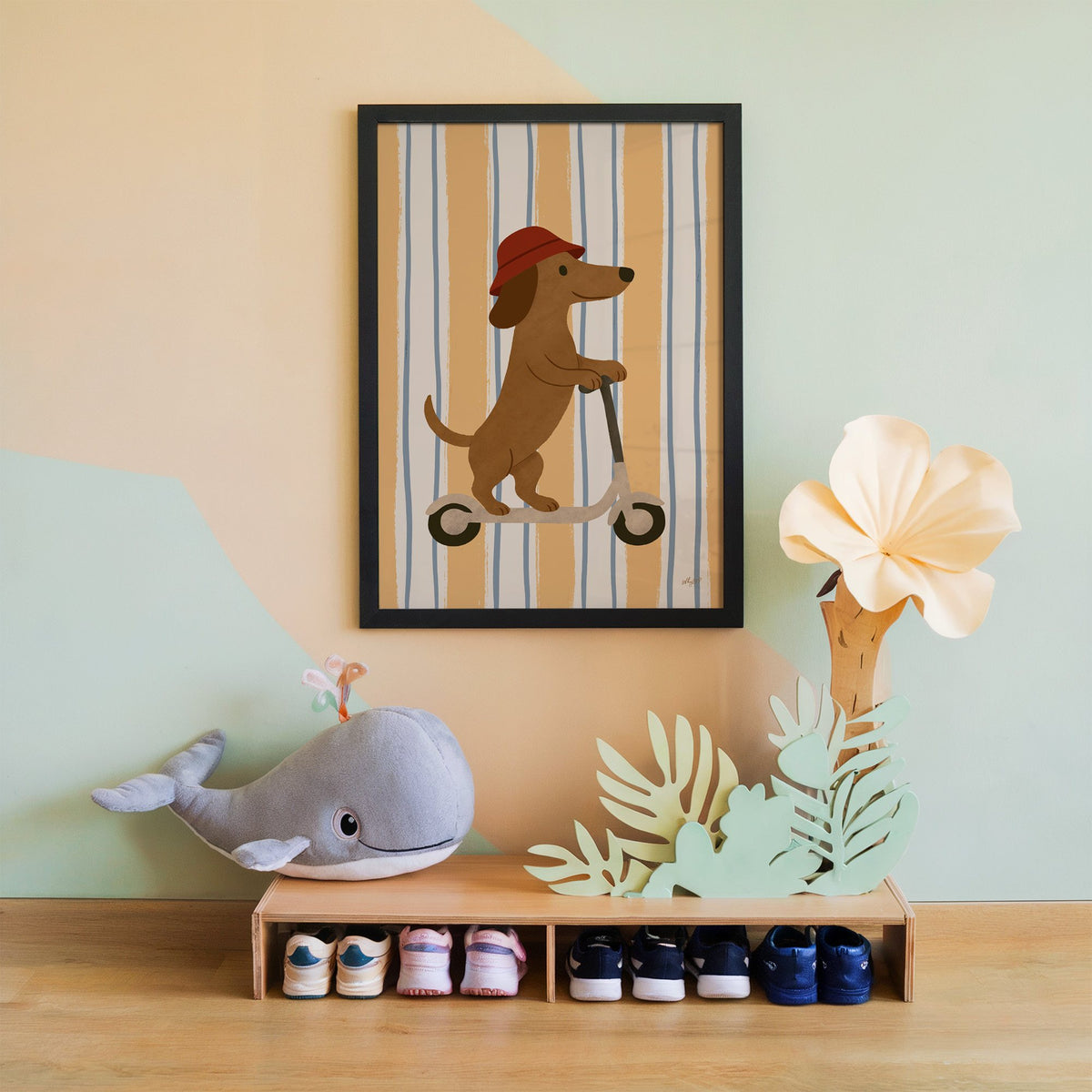 Dachshund riding scooter on stripes nursery print in a black frame on a mint and peach wall above a whale plush