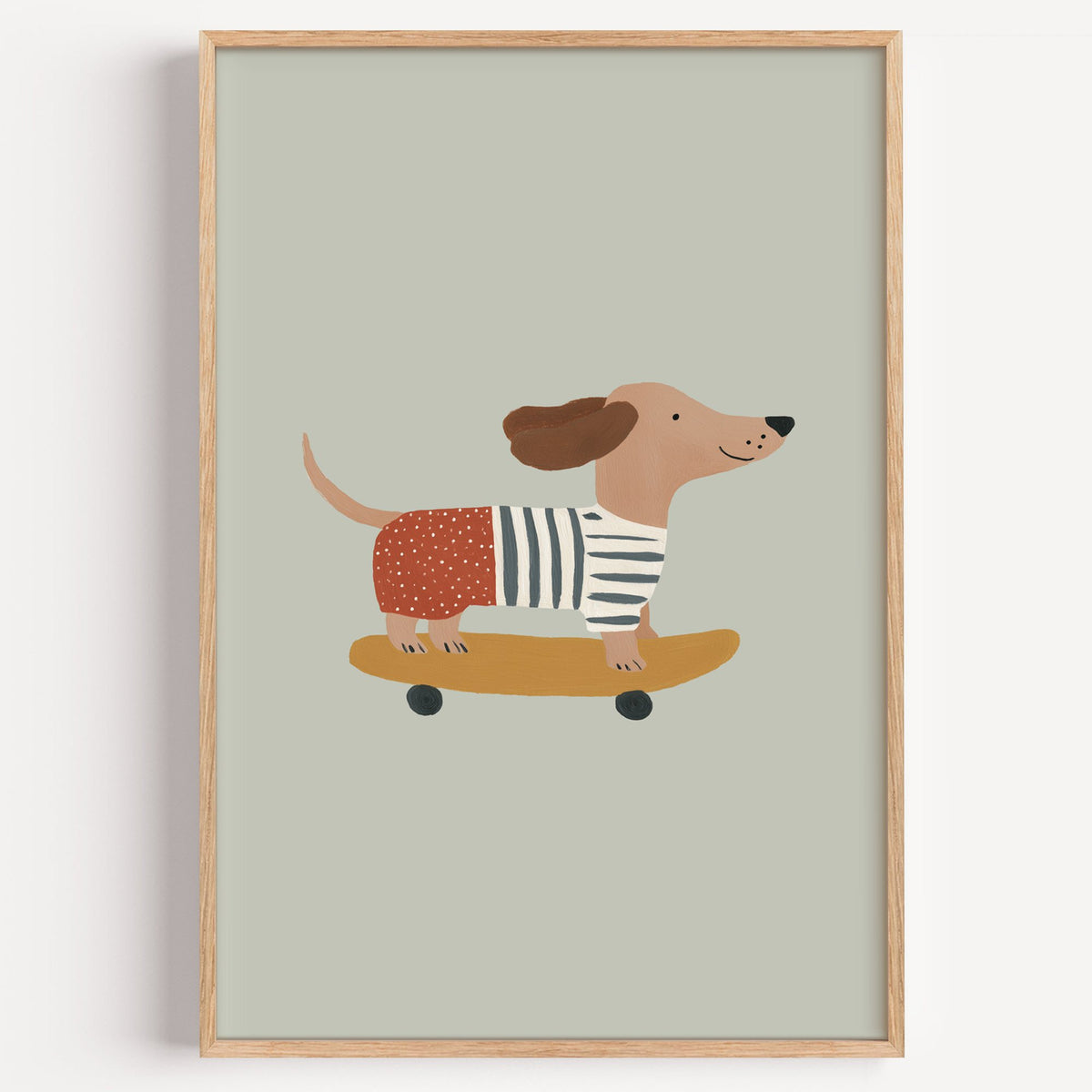 Dachshund skateboard sage nursery print in a light oak frame on a plain white wall