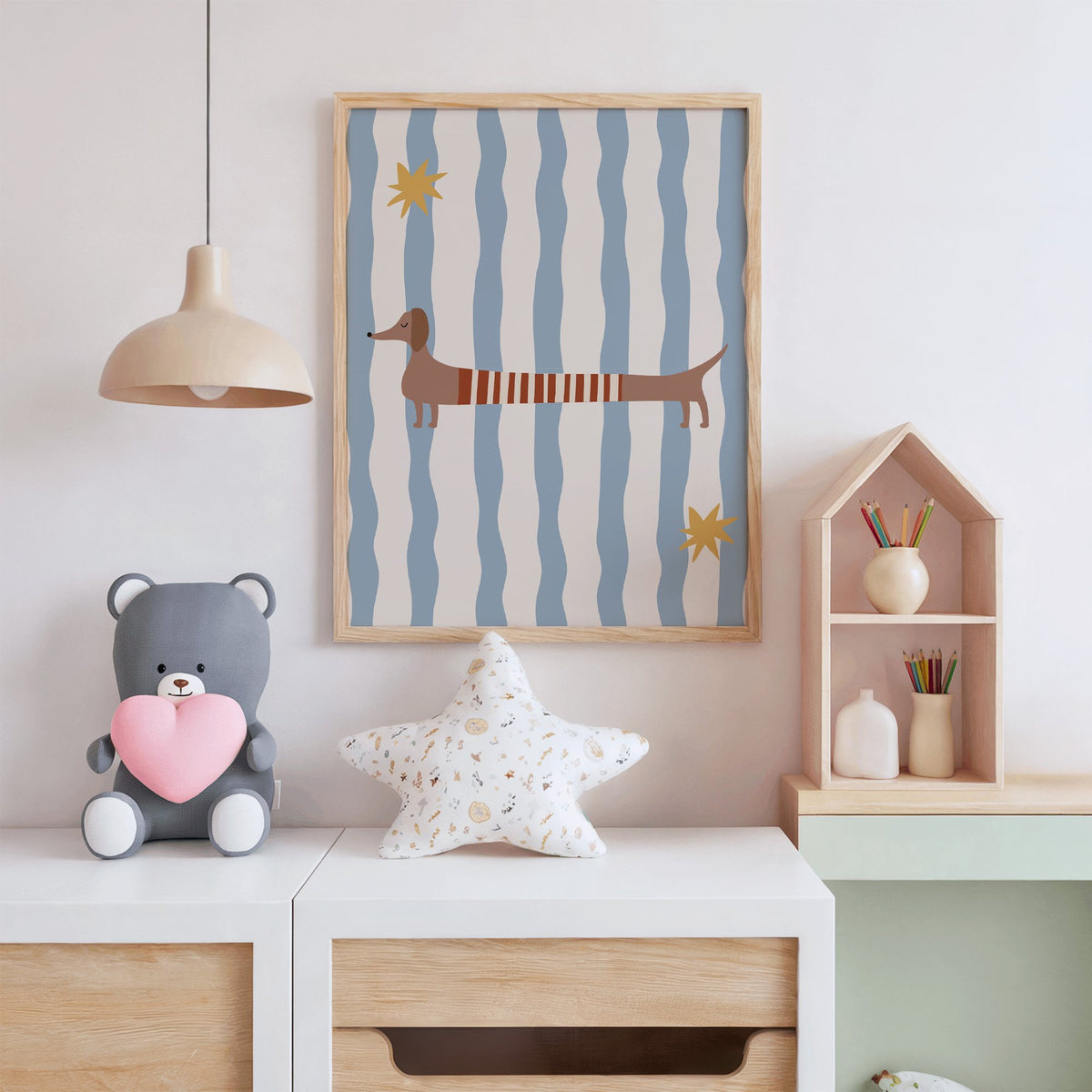 Dachshund red striped sweater nursery print in an oak frame above a white dresser with a star pillow and house shelf