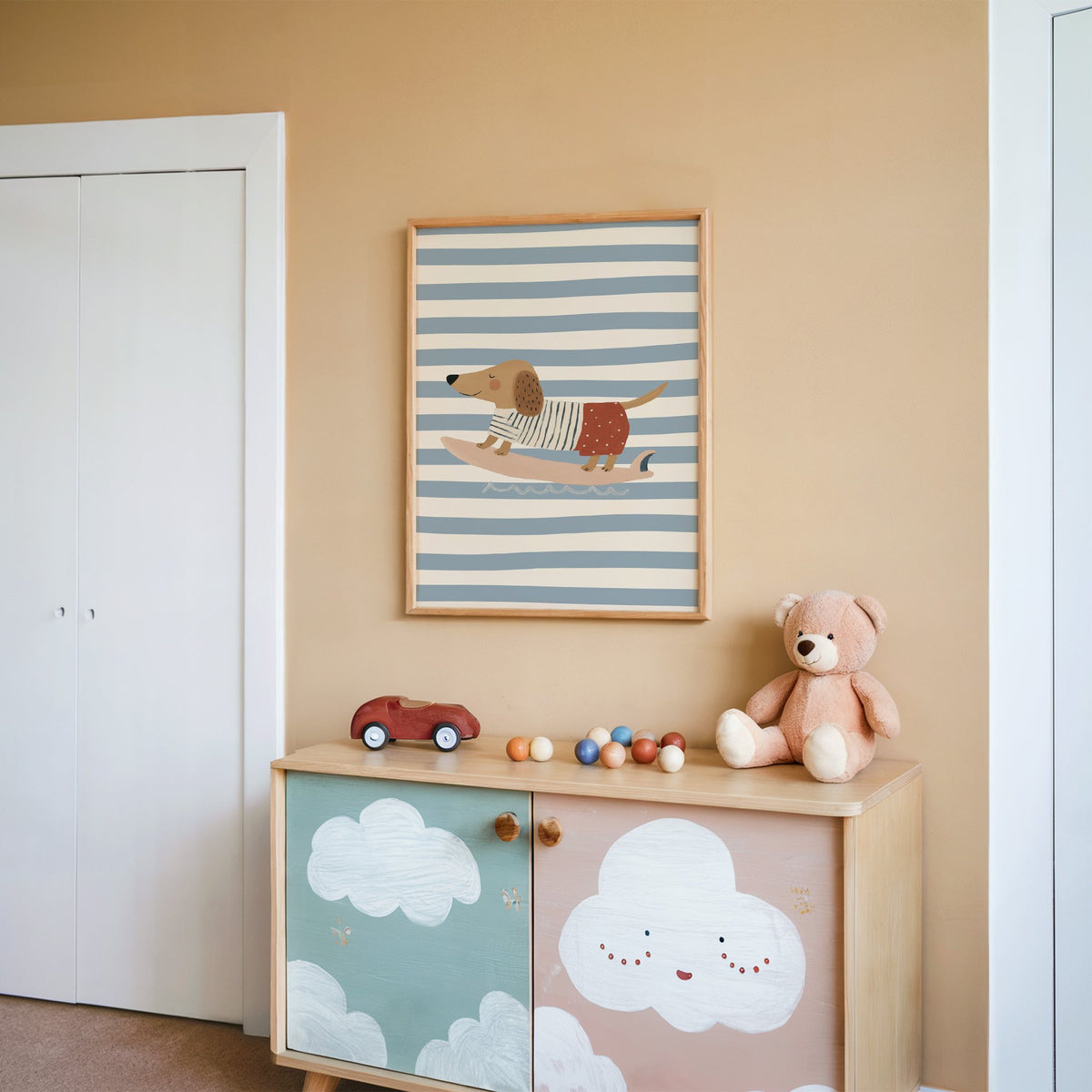 Dachshund on pink surfboard nursery print in an oak frame on a peach wall above a cloud-painted cabinet