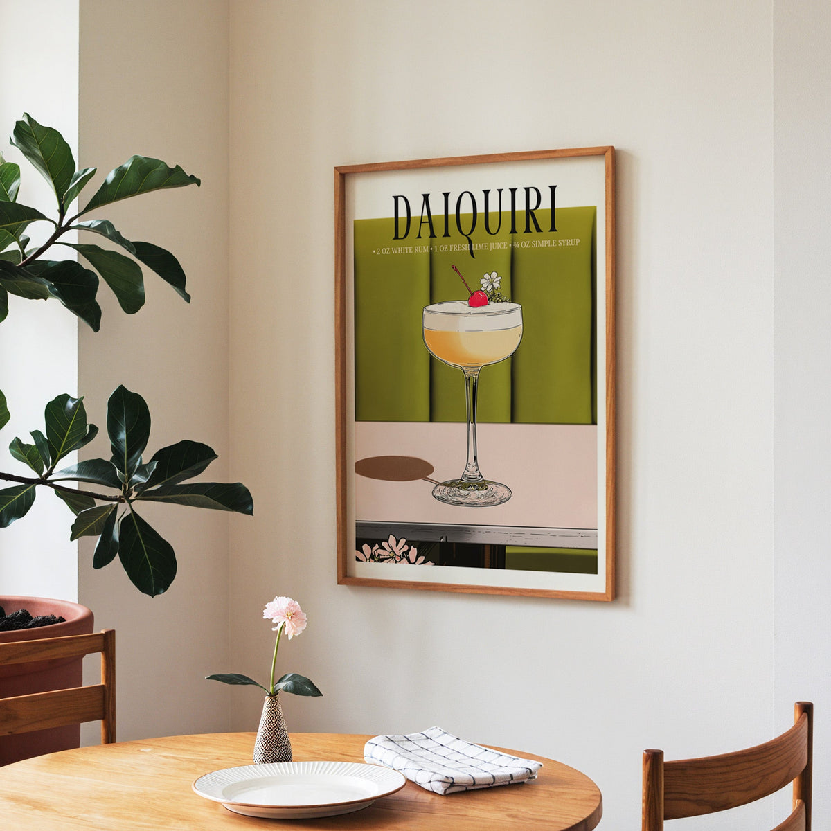 Daiquiri recipe print in a walnut frame above a round table beside a fiddle-leaf fig