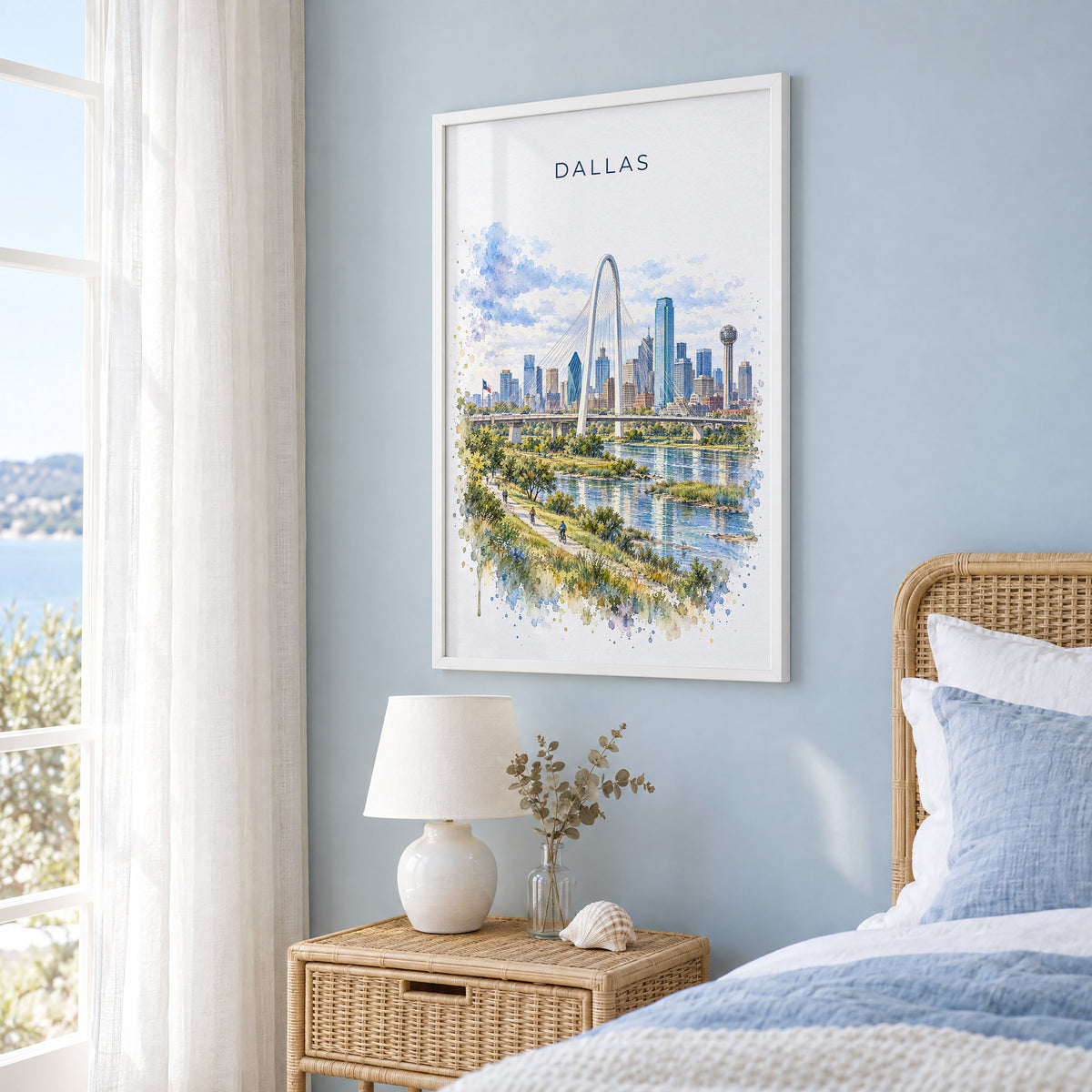 Dallas watercolor print in a white frame on a pale blue wall beside a rattan bed in a coastal bedroom