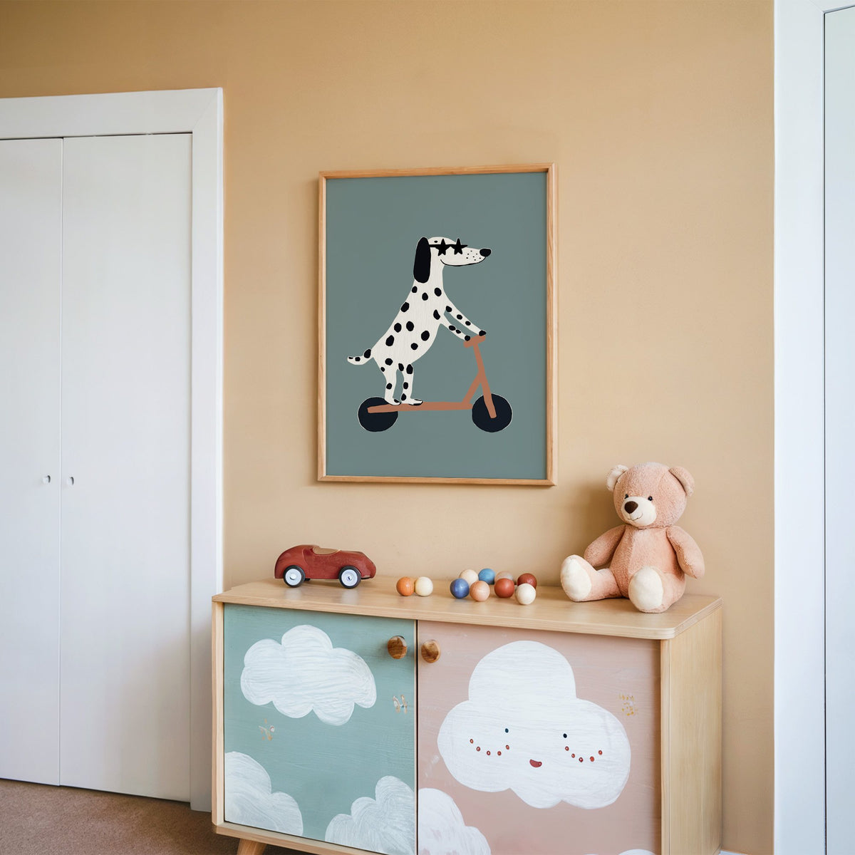 Dalmatian on scooter star glasses nursery print in an oak frame on a peach wall above a cloud-painted cabinet