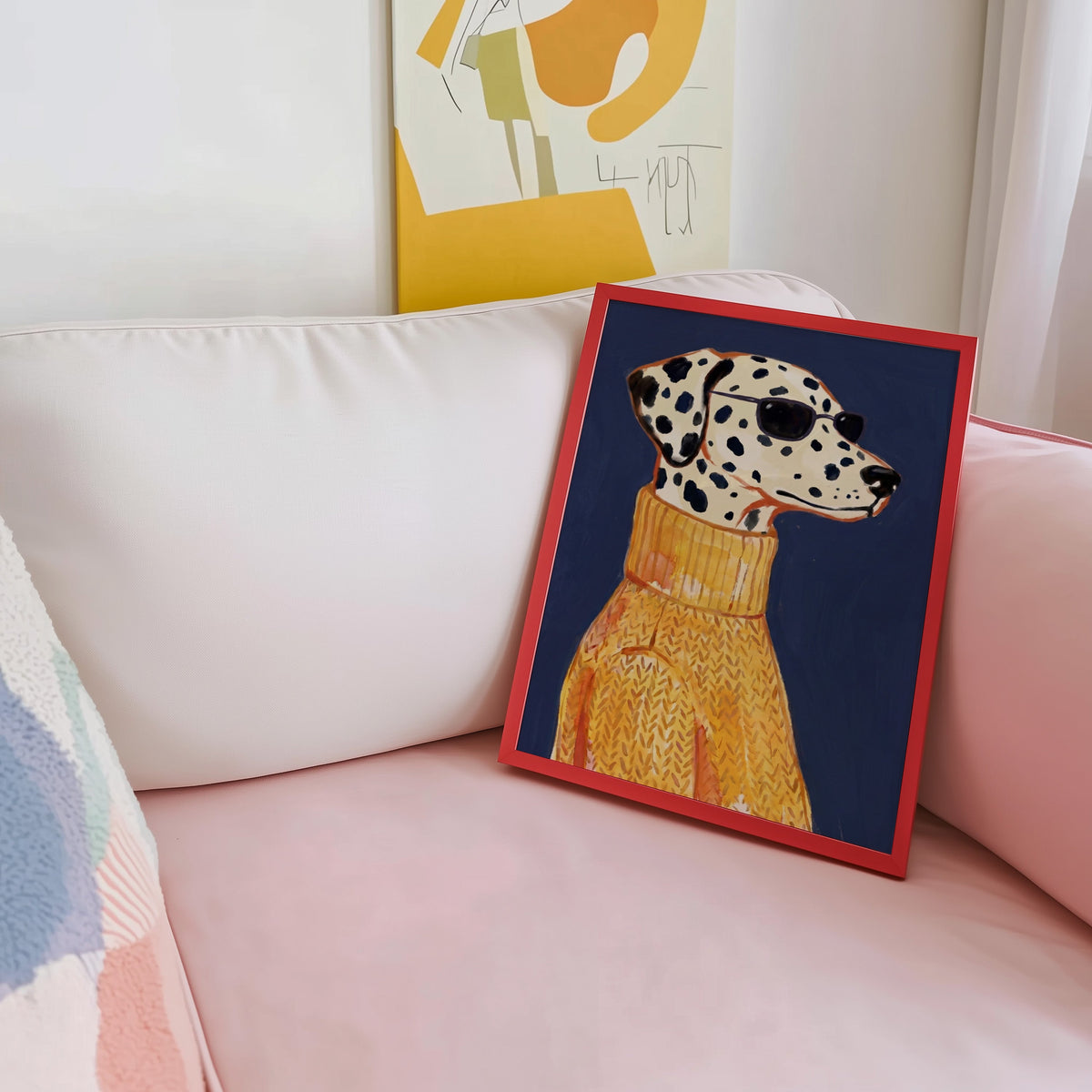 Fashion dog portrait print shown in a red frame leaning on a blush pink sofa