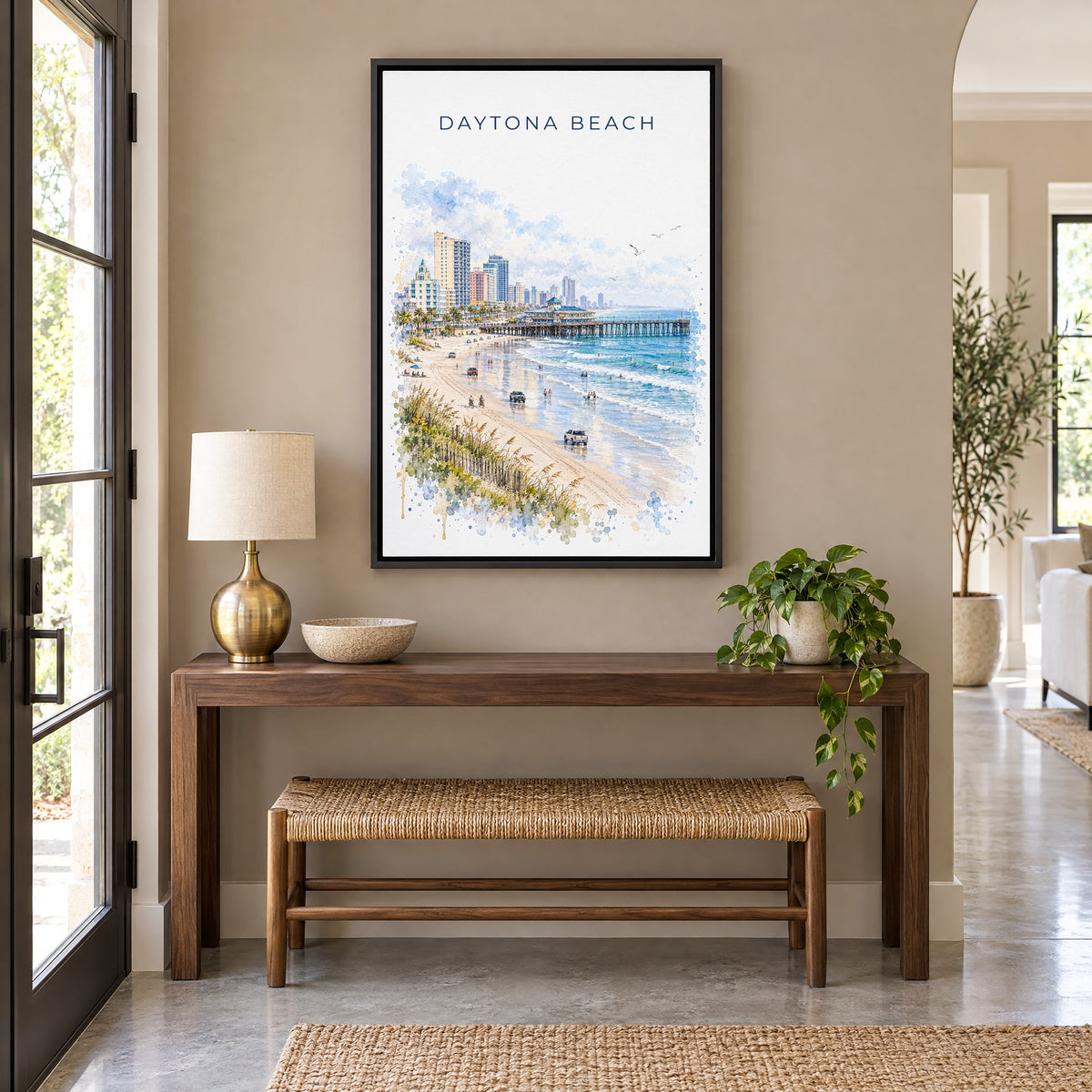 Daytona Beach watercolor print as a black floater canvas above a walnut console and woven bench in an entryway